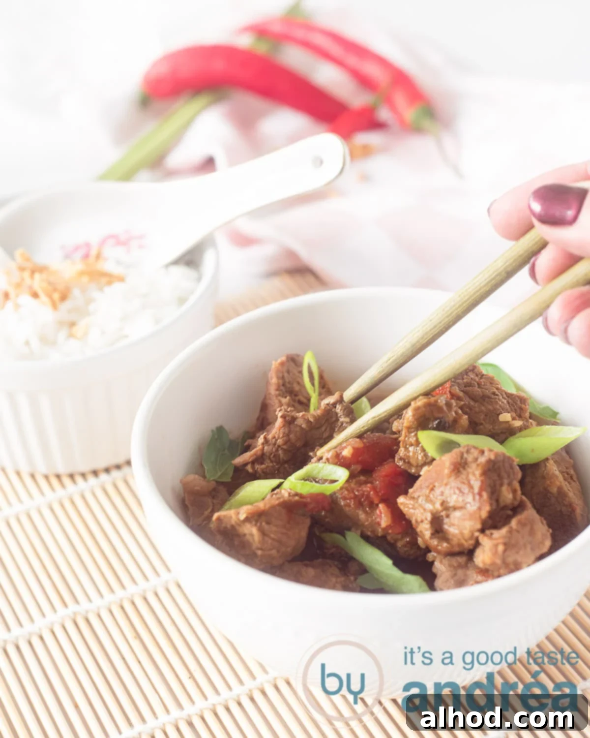 Sweet & Savory Slow-Simmered Beef 6 A white bowl filled with Indonesian stew, behind it a bowl filled with rice. A wicker mat underneath.