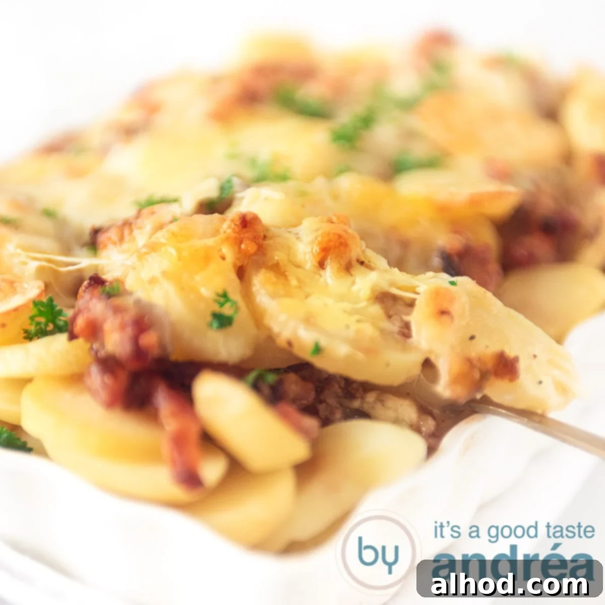 Creamy Dutch Potato and Ground Beef Casserole 6 een vierkante fotoEen lepel die een hap aardappel anders uit de witte ovenschaal pakt