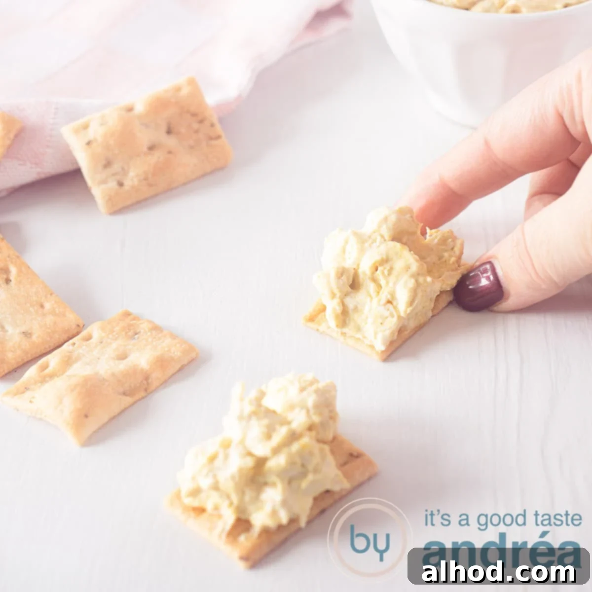 The Ultimate Curry Chicken Salad Sandwich 6 A square picture with two toasts with chicken curry salad. A hand taking one toast.