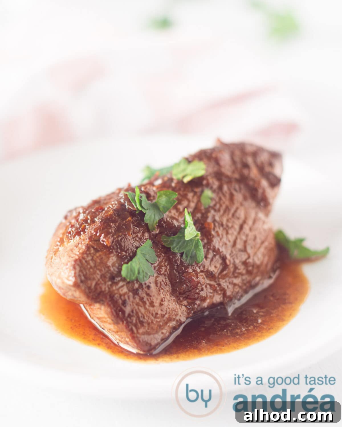 An appetizing elevation photo of a perfectly cooked steak, drenched in its signature rich brown gravy and delicately garnished with fresh green parsley, presented on an elegant white plate against a crisp white background. The dish looks vibrant and ready to be enjoyed.