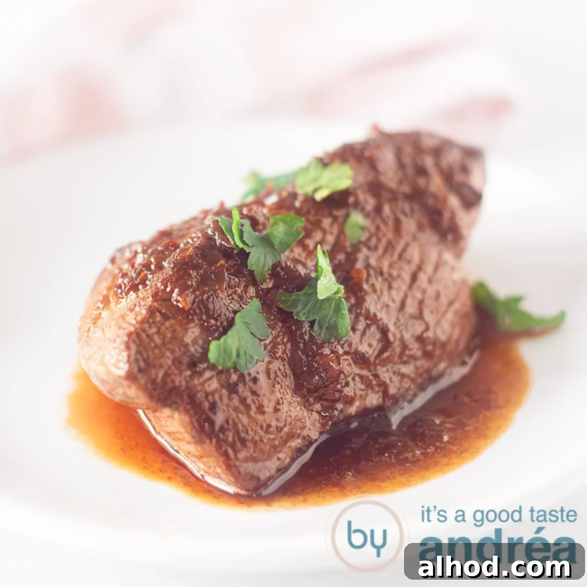 A beautifully presented Loetje's style steak on a white plate, ready to be served. A pink and white tea towel is in the background, adding a touch of domestic warmth to the scene.
