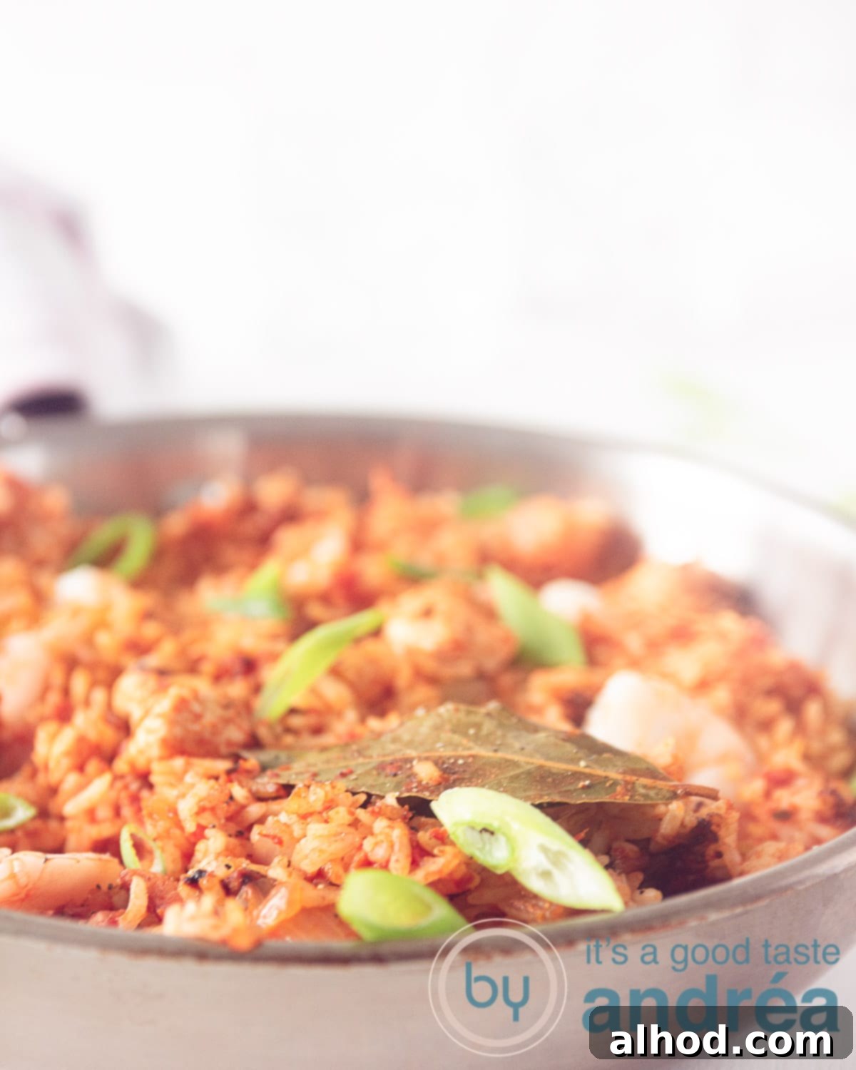 Classic Chicken, Shrimp, and Sausage Jambalaya Recipe 5 A macro photo of a pan filled with Jambalaya rice with shrimp, chicken and sausage. Garnish with spring onion on a white background, highlighting the vibrant colors and textures.