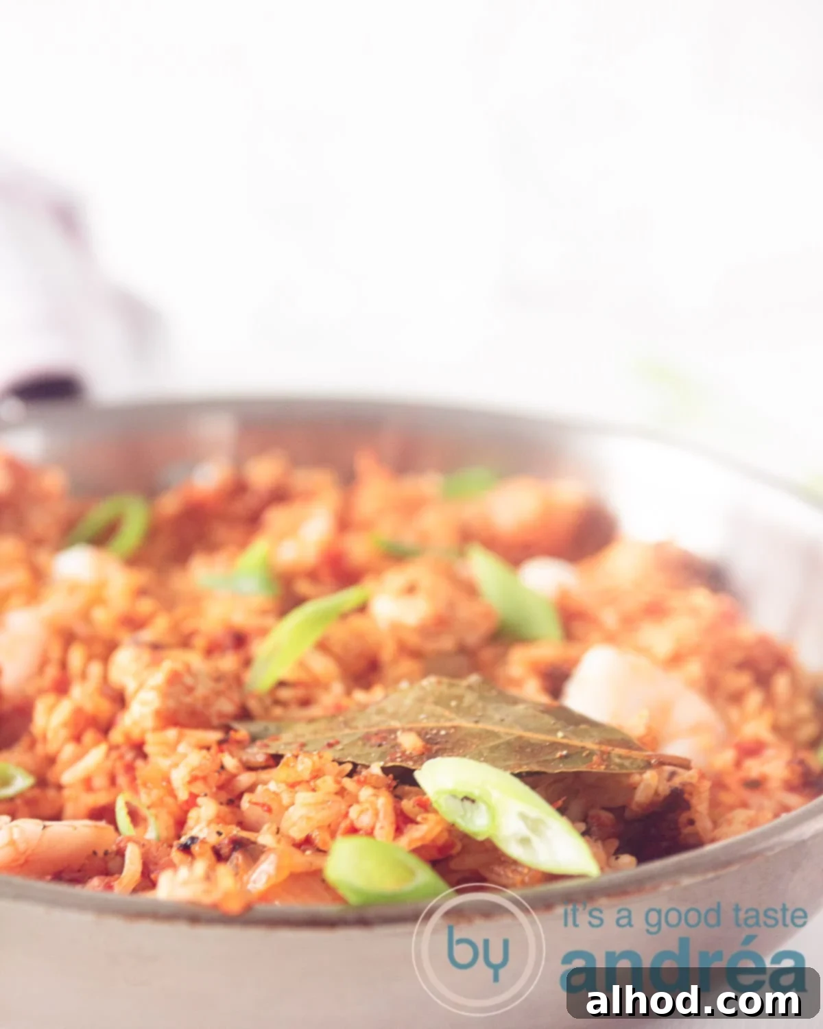 Classic Chicken, Shrimp and Sausage Jambalaya 5 A macro photo of a pan filled with Jambalaya rice with shrimp, chicken and sausage. Garnish with spring onion on a white background