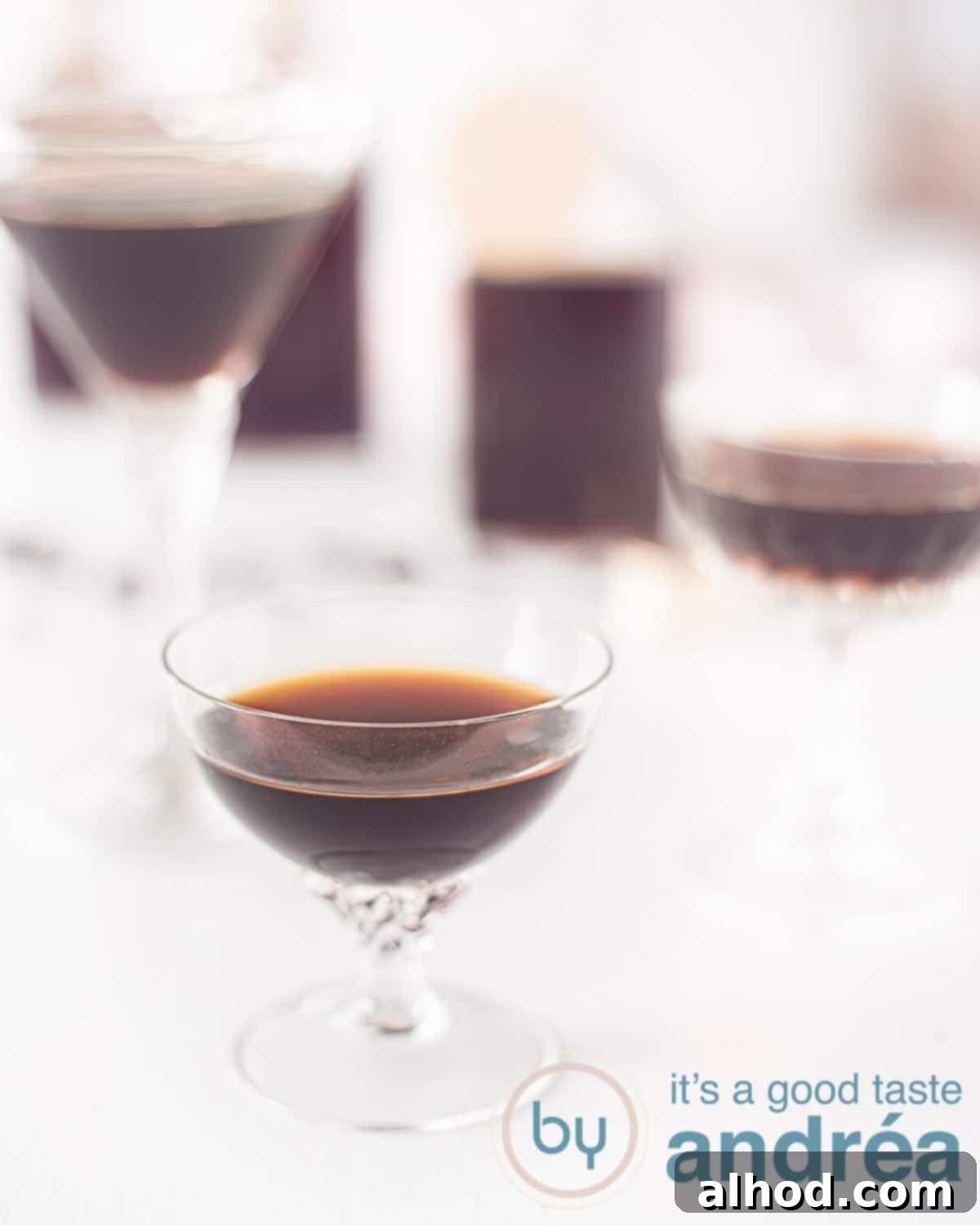 All glasses filled with Tia Maria on a white background. In the background bottles filled with Tia Maria