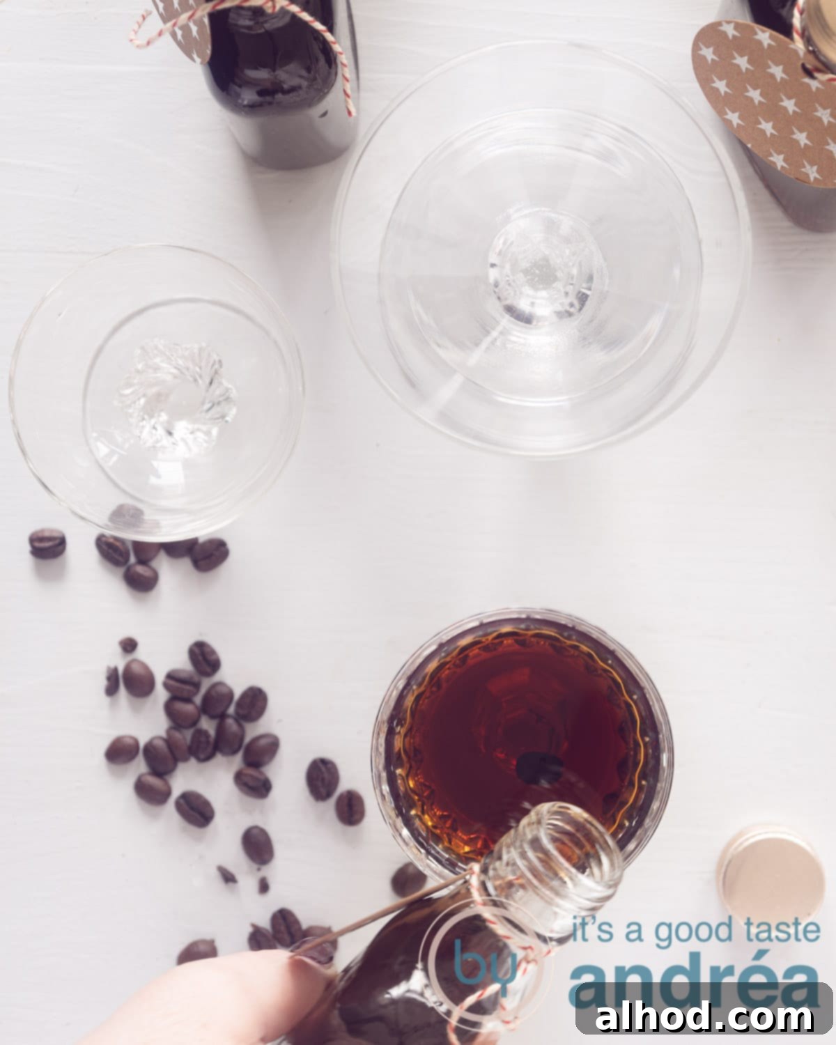 A photo from above showing three glasses, the first being filled with coffee liqueur. Some coffee beans on the white background