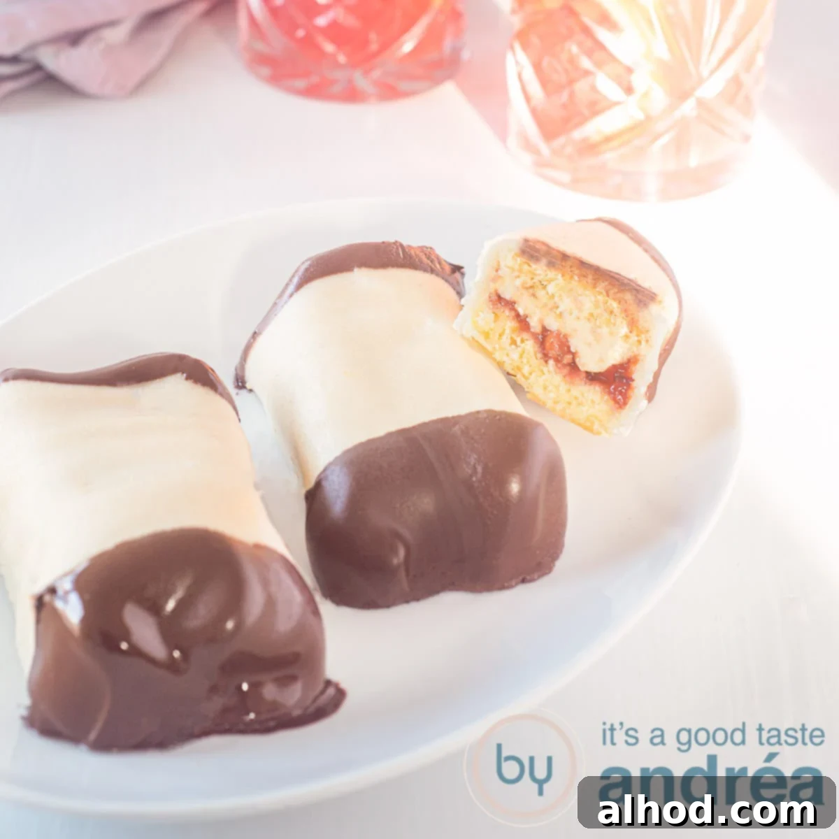 A square photo of a dish with two Mergpijpjes and a half of a third one resting on top, on a white background.