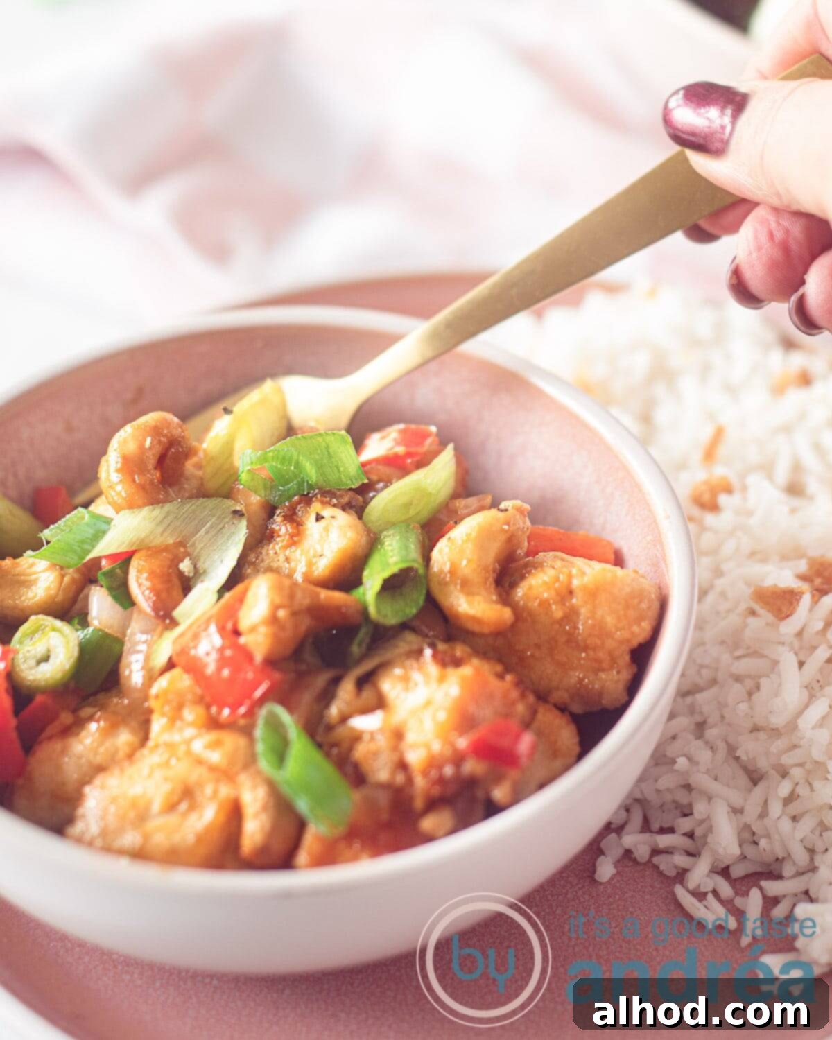 15-Minute Spicy Cashew Chicken 2 A pink dish filled with Thai chicken in a delicious spicy sauce. On a pink plate with rice
