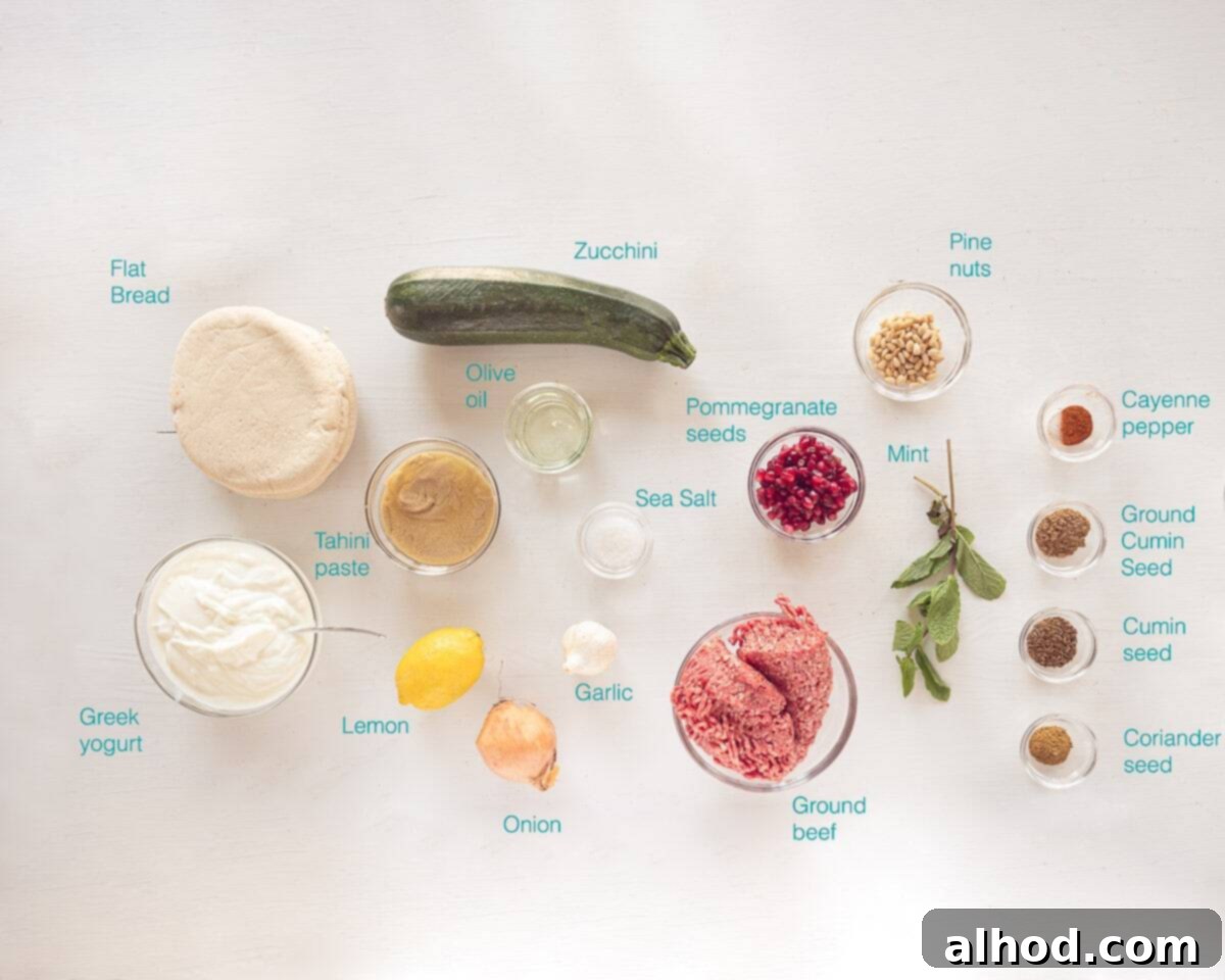 Hearty Zucchini Fatteh with Spiced Beef 3 A flat lay photograph showcasing all the fresh produce, spices, and other essential ingredients neatly arranged on a white background, ready to prepare Zucchini Fatteh with Ground Beef.