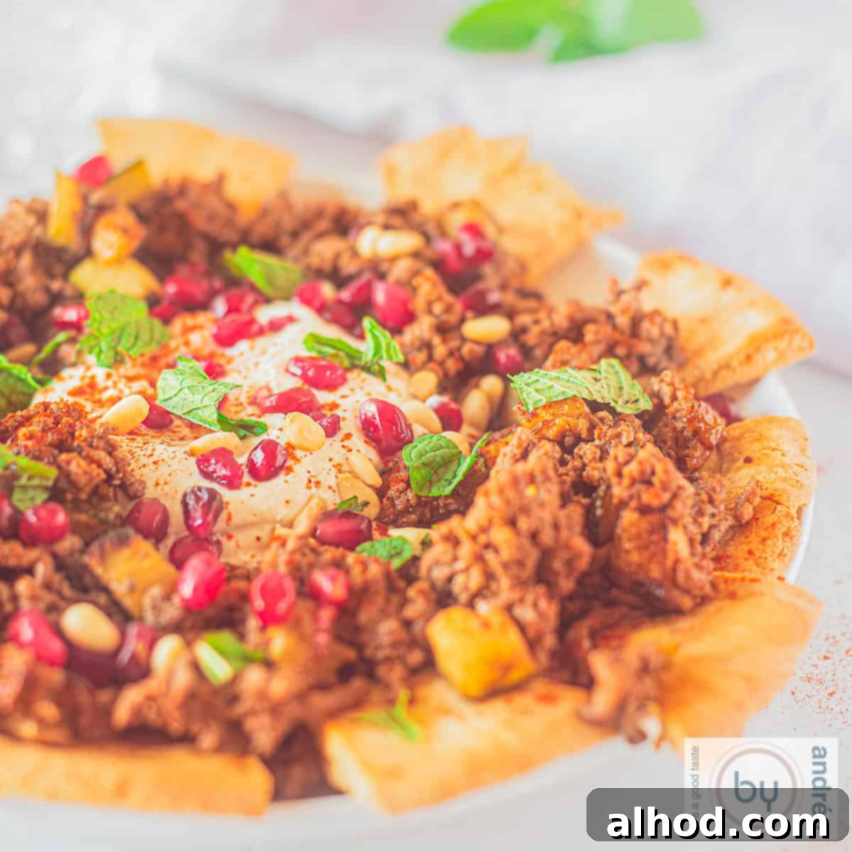 Kabaklı Kıymalı Fatteh Ortadoğu Sofralarının Gözdesi 6 Een vierkante foto met een bord met pitapuntjes en fatteh met rundergehakt en courgette