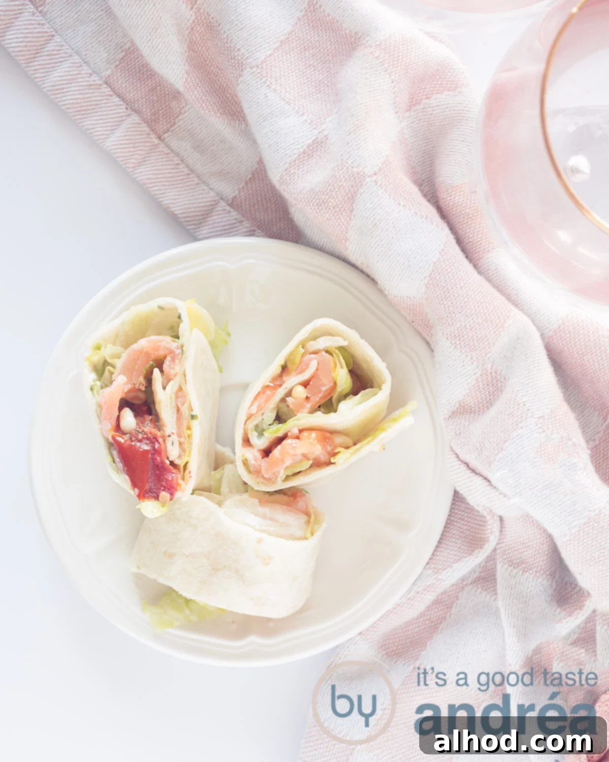 10-Minute Smoked Salmon Pinwheels 2 Three delicious wrap rolls with smoked salmon and iceberg lettuce on a black plate on a black background, garnished with fresh dill.