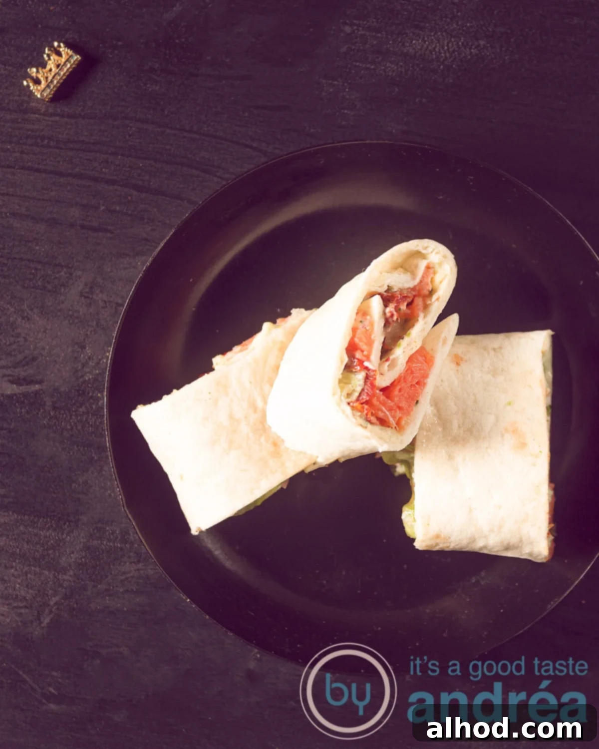 10-Minute Smoked Salmon Pinwheels 5 Three elegantly presented salmon wraps, featuring cream cheese and fresh ingredients, on a sleek black plate against a dark background, ready to be served.