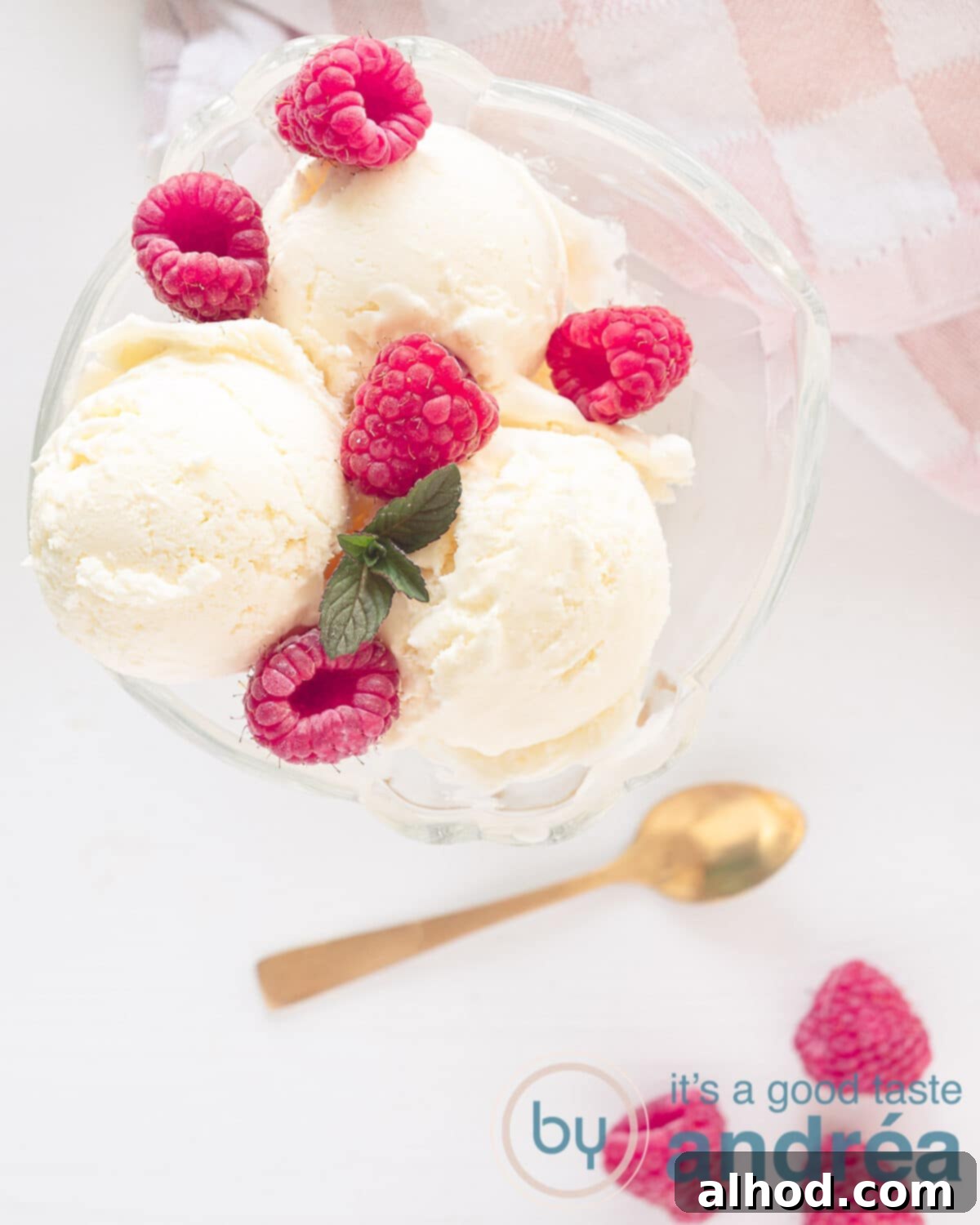 Gourmet Asparagus Ice Cream 2 A photo from above of a glass filled with three scoops of asparagus ice cream, raspberries, a mint leaf on a white background. Some raspberries in the bottom right