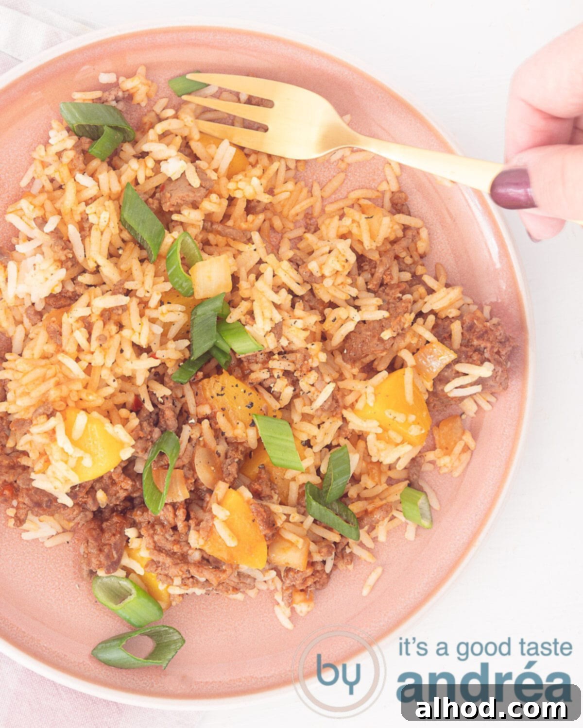 Sweet and Savory Beef Peach Pilaf 2 A photo from above showing a plate full of rice, ground beef, peaches and a golden fork being held by a hand