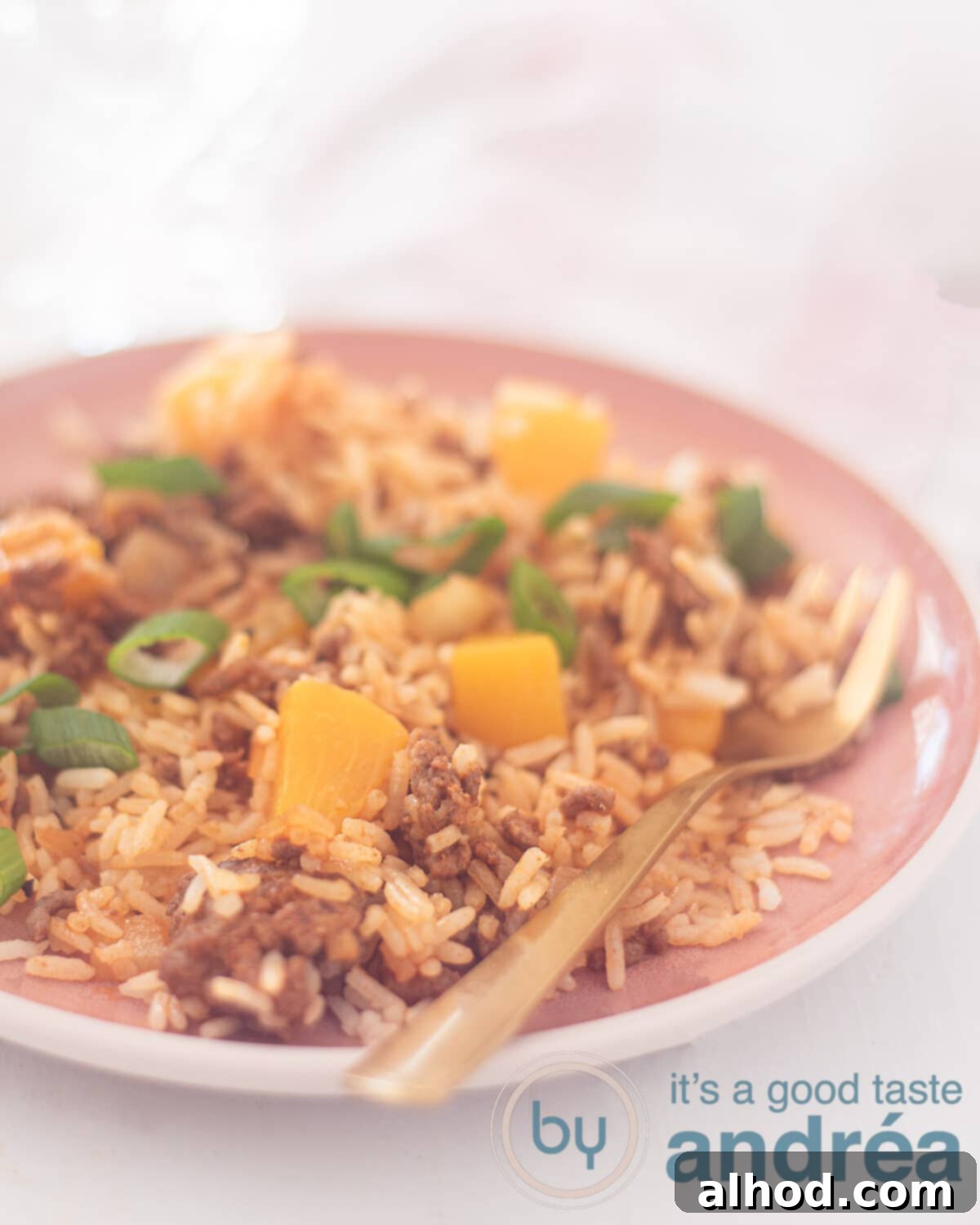 Sweet and Savory Beef Peach Pilaf 5 A photo in the height of a pink plate with pilav rice, minced meat and peaches with a golden fork. A white background and a pink white tea towel in the background