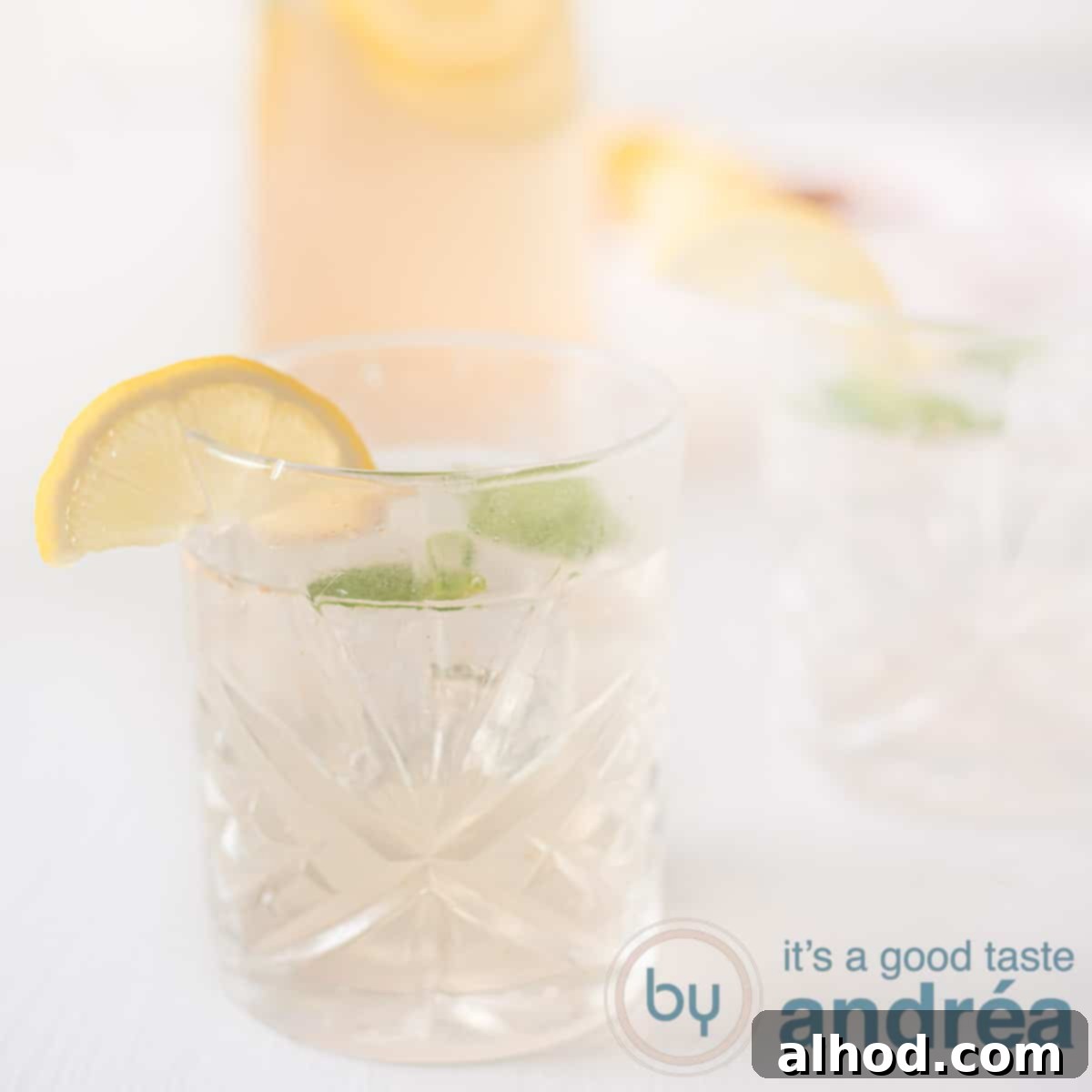 Zingy Ginger Lemonade Syrup 6 A square photo with two glasses of lemon and ginger lemonade with mint and lemon