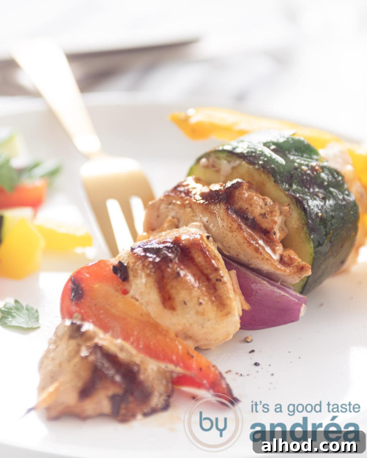 How to Grill Perfect Shashlik 4 A shashlick with vegetable chicken and pork tenderloin on a white plate. A golden fork in the background