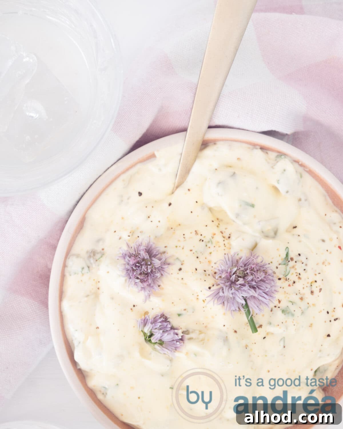 Quick & Easy Tartare Sauce 2 A photo from above of a bowl filled with a sauce tartare, chive flowers and a pink white tea towel