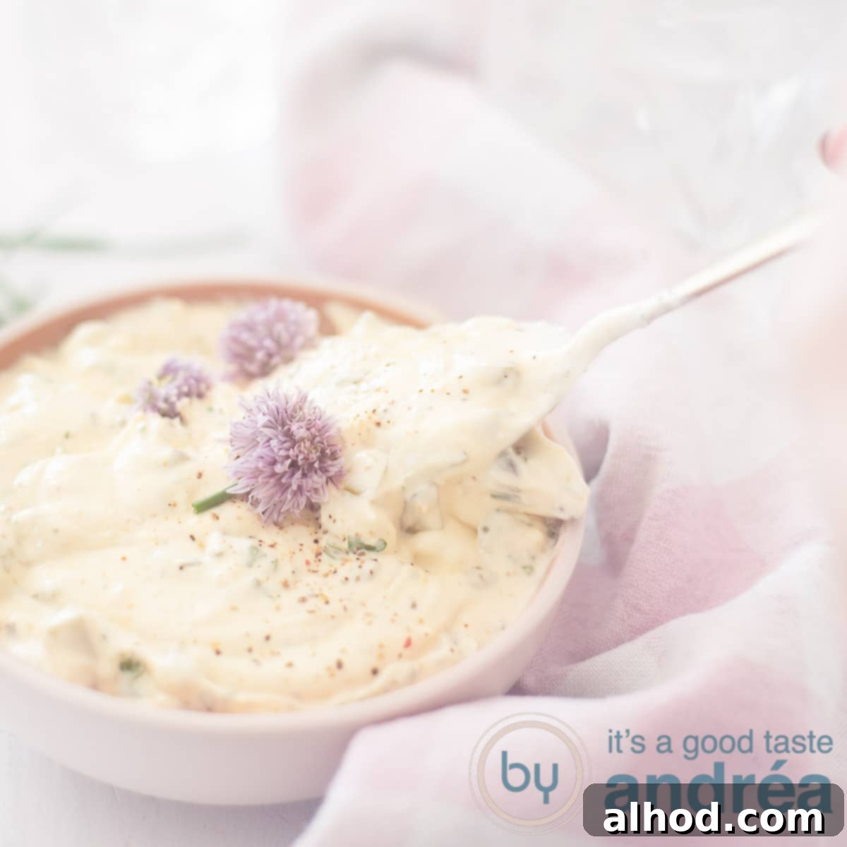 Quick & Easy Tartare Sauce 6 A square photo with a pink bowl filled with tartar sauce with chives flowers and a golden spoon