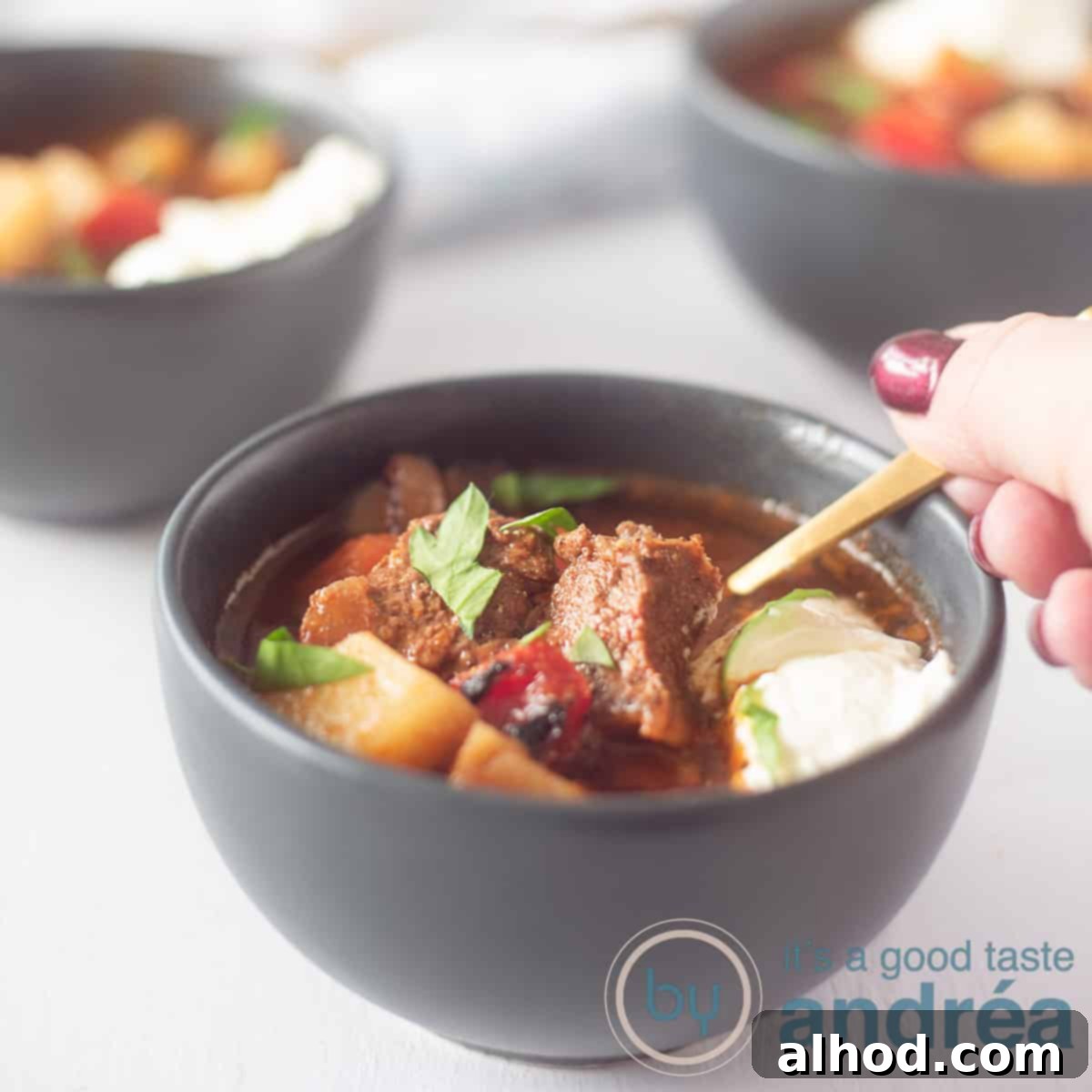 Hearty Slow Cooker Beef Goulash Soup 6 a square photo of a grey bowl filled with Hungarian Goulash soup with beef, potato and sour cream.