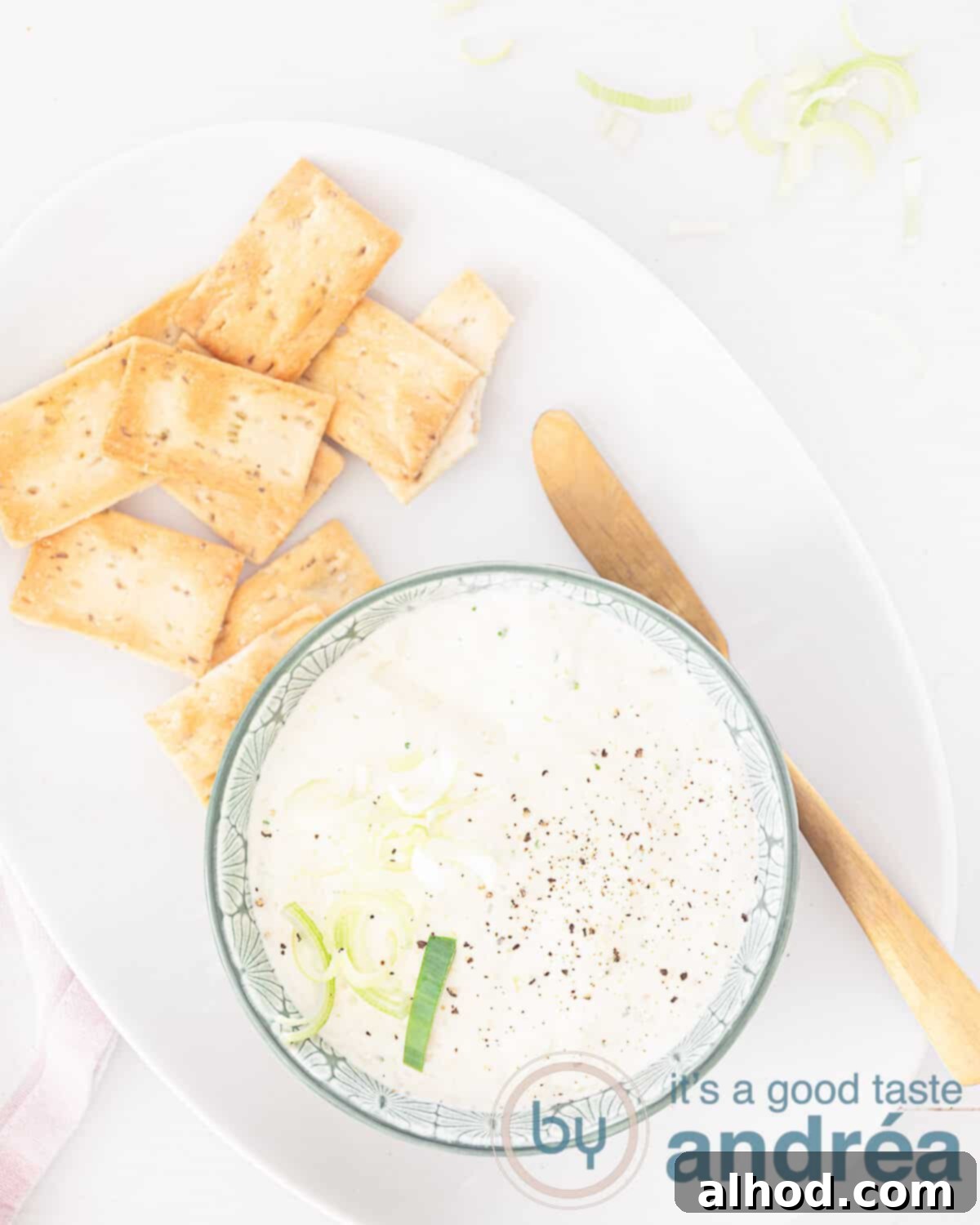 Dutch Farmhouse Leek Dip 2 A photo from above. At the bottom of a green dish filled with a cream cheese spread with leek. top left some toasts on a white dish.