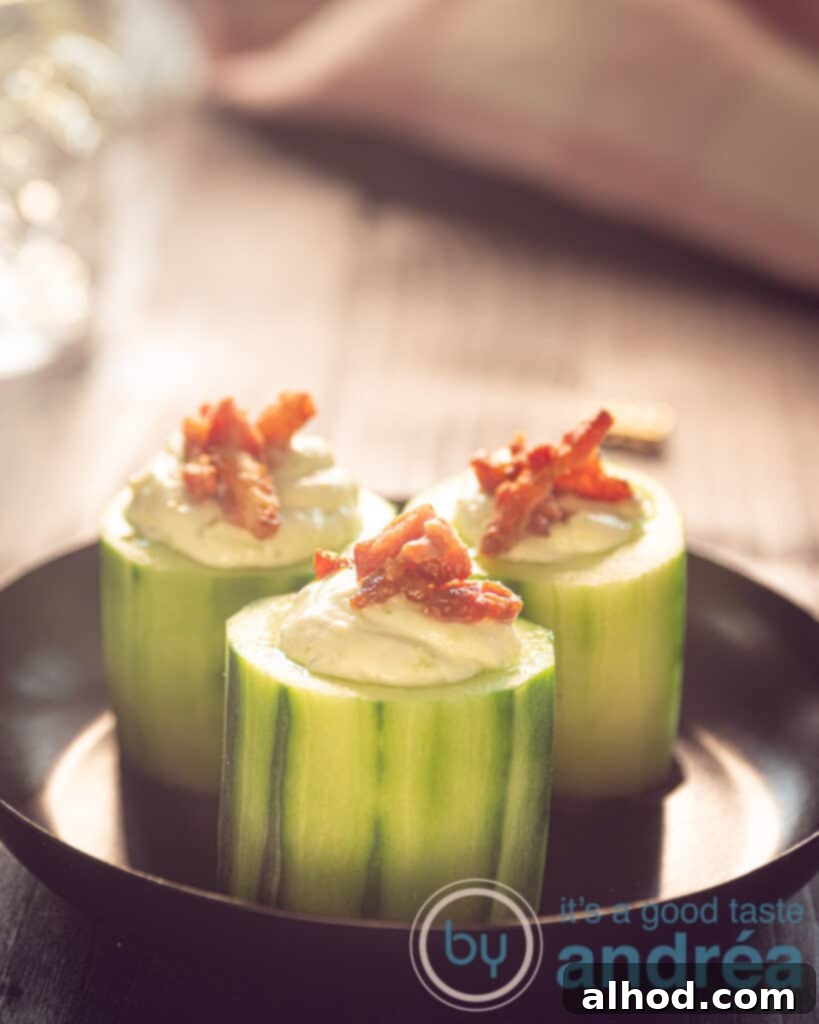 Leek Dip Cucumber Bites with Crispy Bacon 2 Three cucumber appetizers with leek dip and topped with bacon on a black plate, ready to be served.