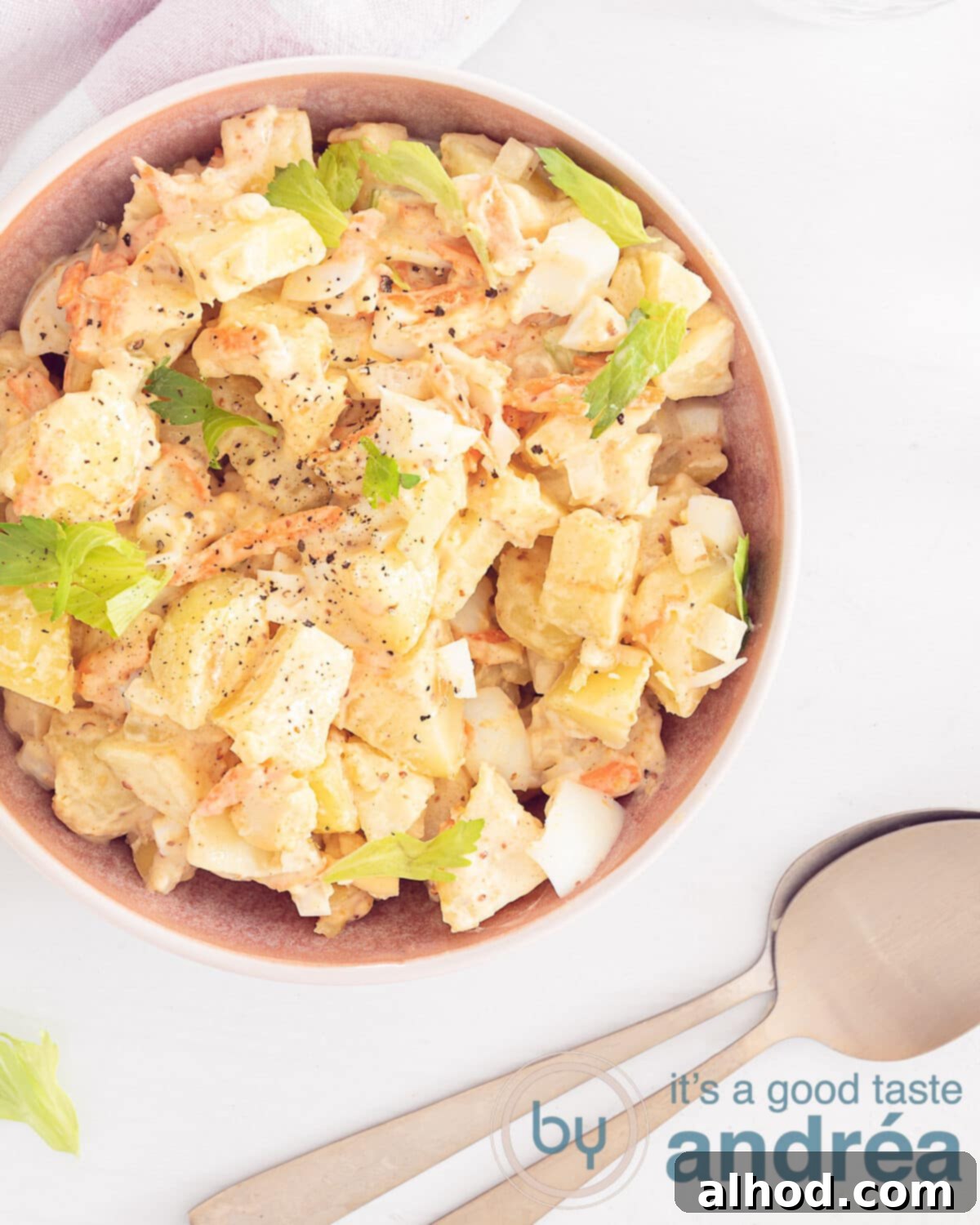 Amish Potato Salad 2 Delicious creamy Amish potato salad with visible celery, hard-boiled egg, and carrot pieces on a white background, viewed from above.