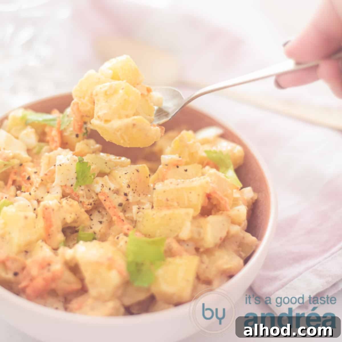 Amish Potato Salad 6 A square photo of a pink bowl filled with creamy Amish potato salad, with a spoon taking a scoop.