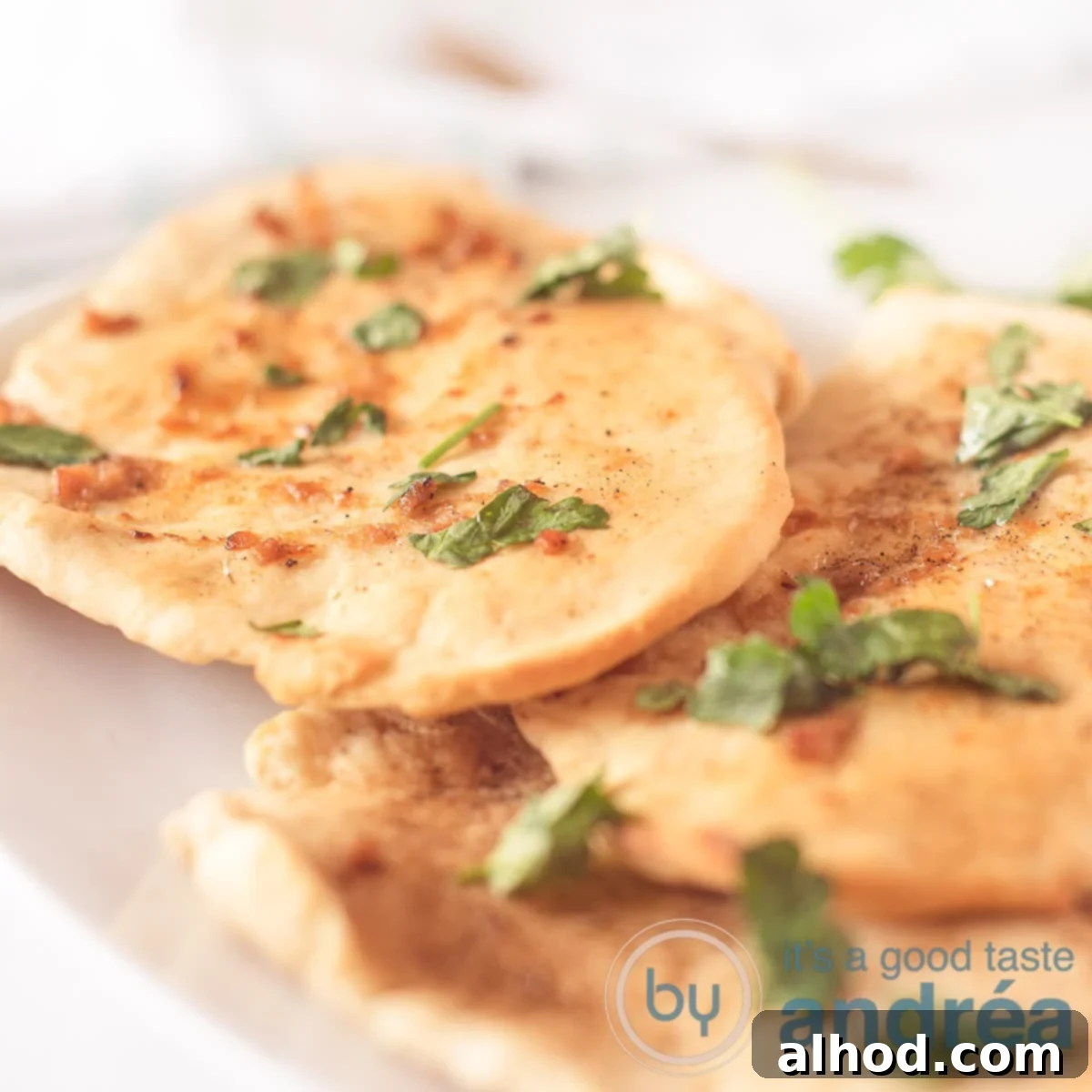 Buttery Garlic Herb Naan 6 A square photo with three naan sandwiches with garlic parsley butter on a white tray on a white background