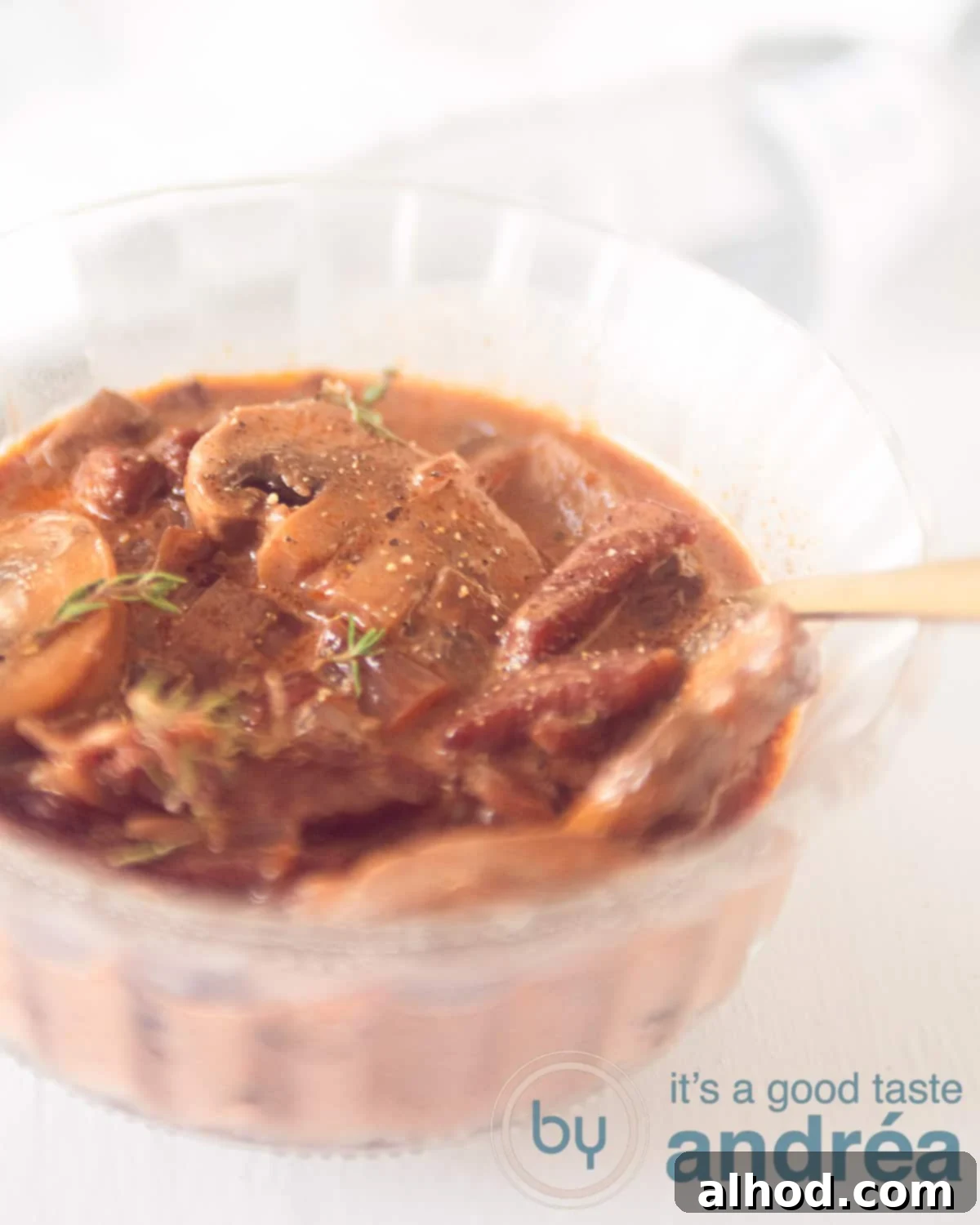 Part of a glass dish filled with hunting sauce with mushrooms on a white background
