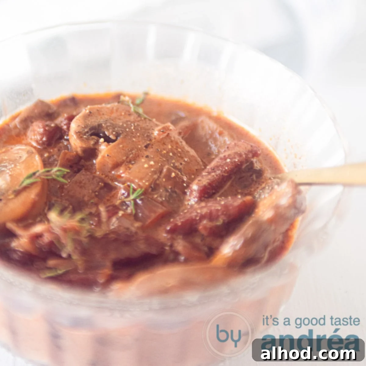 A glass dish filled with brown hunter sauce with mushrooms and thyme.