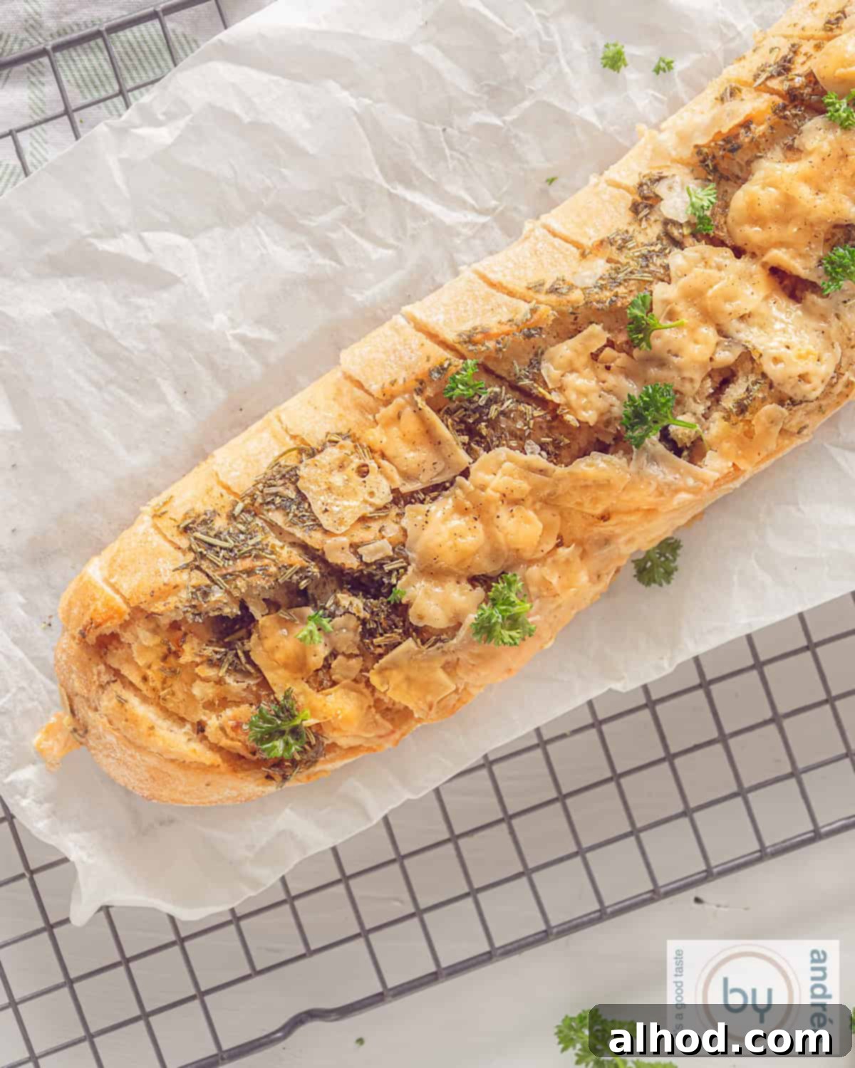 Herbed Garlic Baguette 3 An overhead shot of a freshly baked baguette, richly coated with herbs and garlic, presented on a baking sheet, ready to be enjoyed by eager hands.