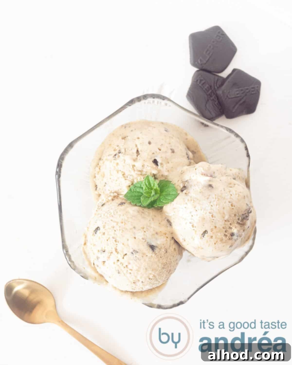 No-Churn Dutch Licorice Delight 5 An overhead shot showcasing three perfectly scooped servings of creamy licorice ice cream in an elegant black glass dish, accompanied by a golden spoon on the bottom left and a subtle decorative element in the top right corner.