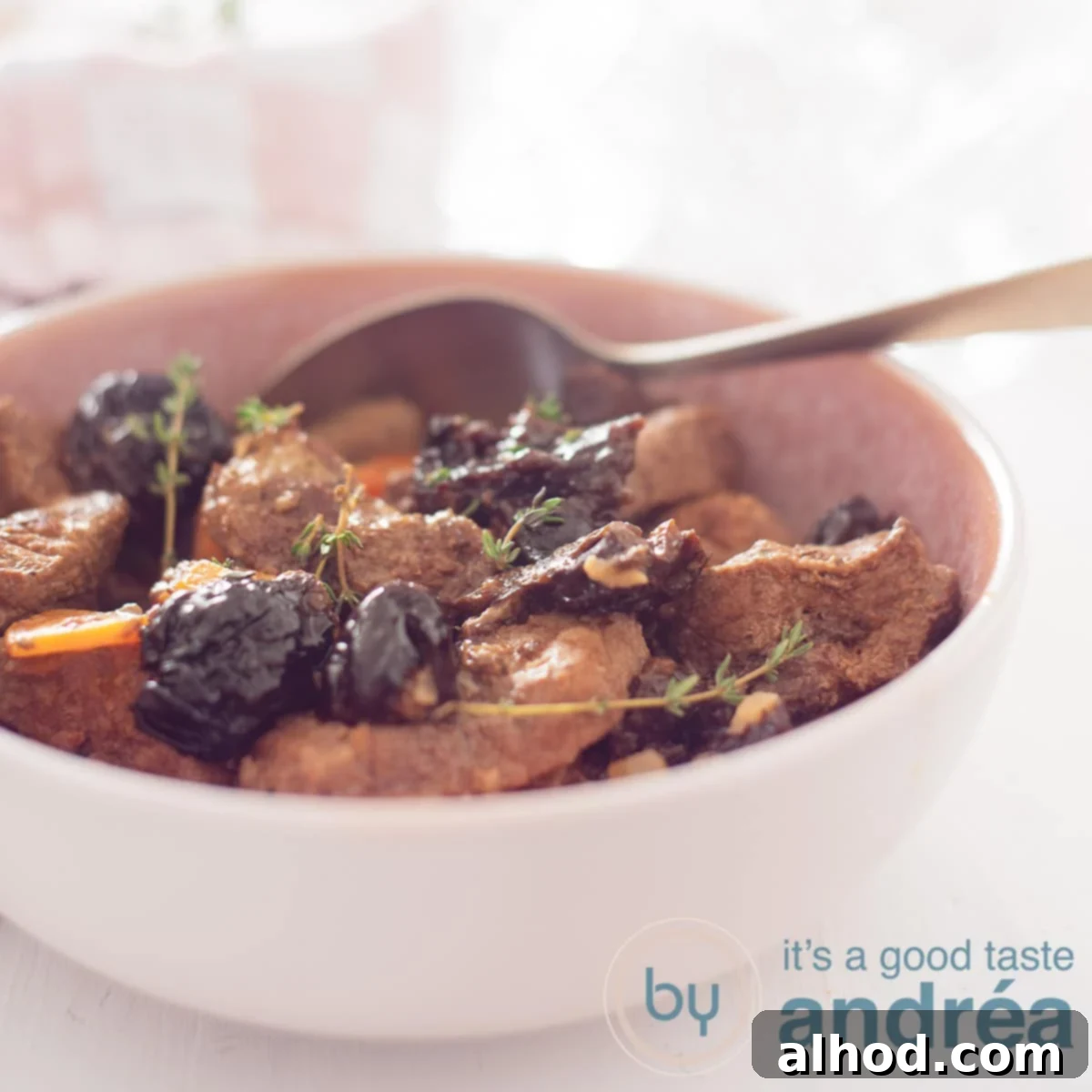 Tender Slow Cooker Plum Pot Roast 6 A square photo with a pink dish filled with beef stew, plums and carrot. A golden spoon sticks in it.