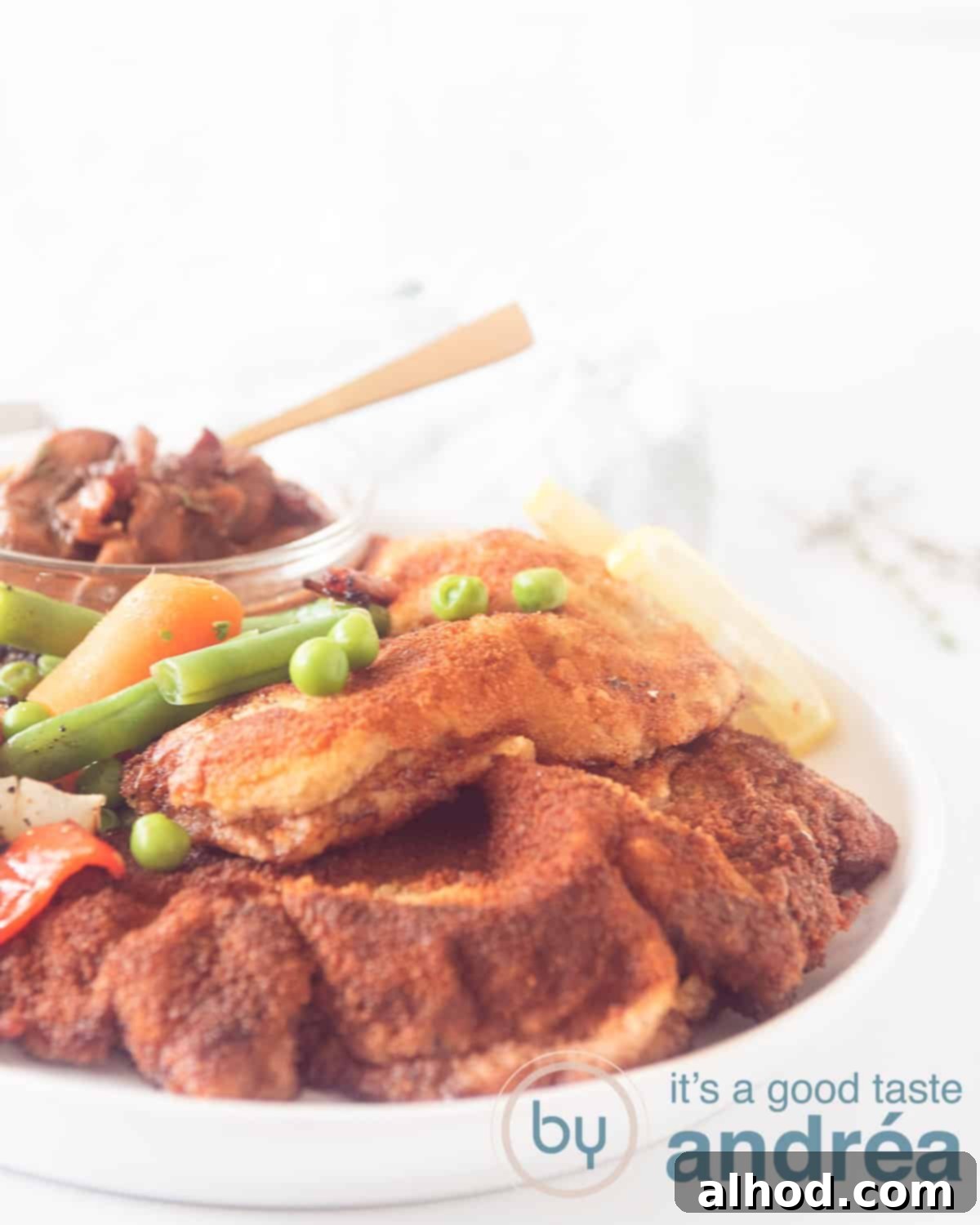 Easy German Jägerschnitzel 4 An aerial view showing part of a white plate with hunter schnitzels, hunter sauce and fresh vegetables on a white background