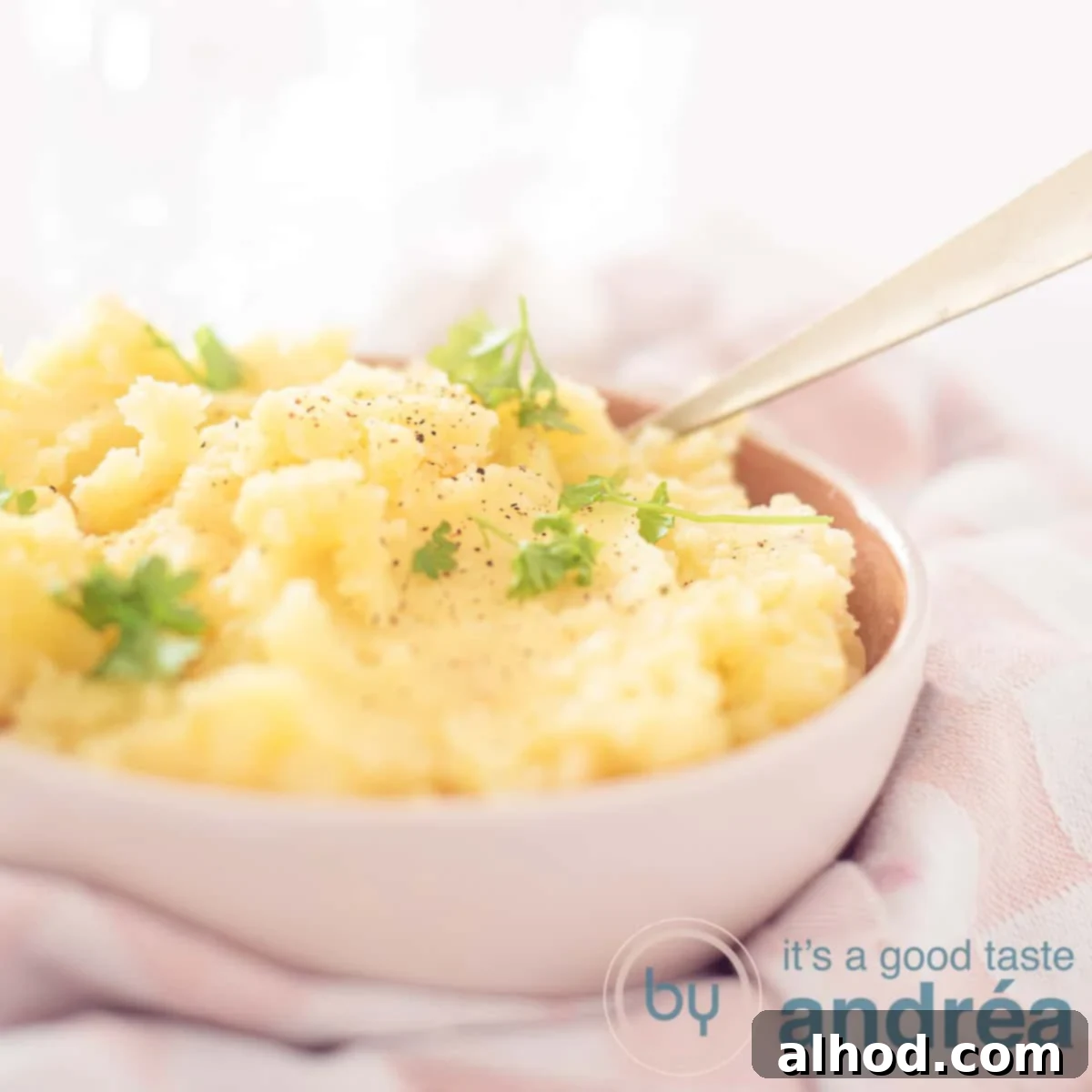 Aromatic Garlic-Shallot Mashed Potatoes 6 A square photo with a pink bowl filled with mashed potatoes with shallot and garlic. Garnished with parsley. And with a pink and white checkered tea towel.