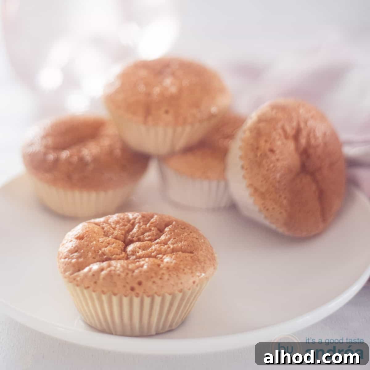 Creamy Milk Cupcakes 4 A square photo with a white plate with five sweet milk cupcakes, one in the foreground, showcasing their delicious golden-brown crust.