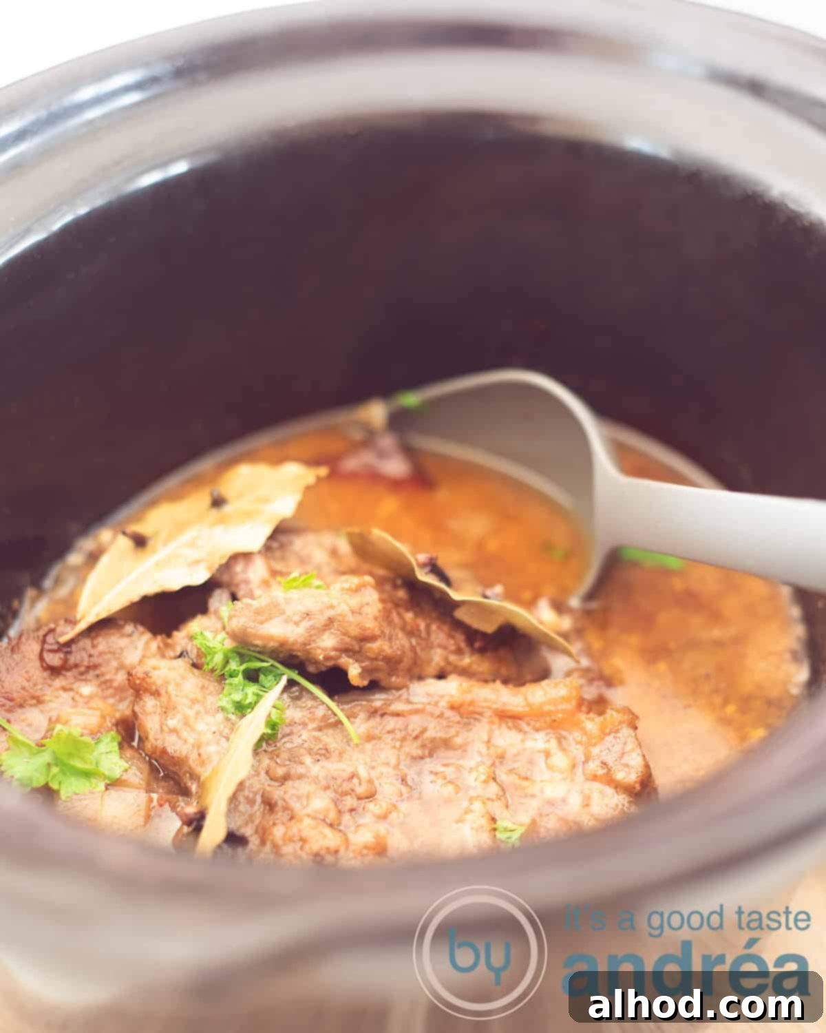 Dutch Slow-Braised Pot Roast 5 A slow cooker filled with Grandma's Dutch draadjesvlees. A gray serving spoon scoops out a bite.