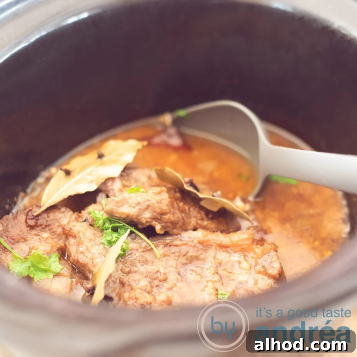 Dutch Slow-Braised Pot Roast 6 A square photo of a slow cooker filled with pot roast in a sauce. A gray spoon sticks into it.