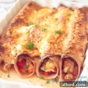 A square photo showing a white baking dish filled with chicken enchiladas in a creamy tomato sauce. au gratin.