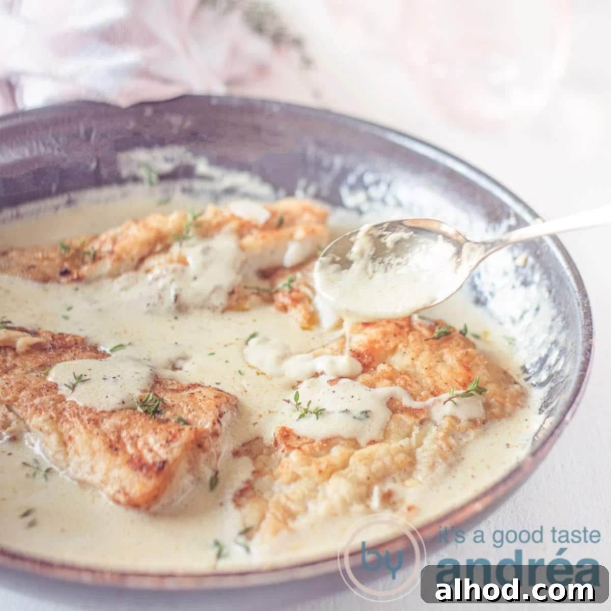 Cod Vin Blanc 6 A square photo with a skillet filled with cod and a creamy white wine lemon sauce.