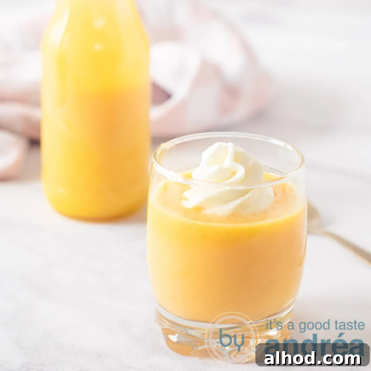 Advocaat Holland's Velvety Egg Liqueur 6 A square photo with a glass filled with homemade eggnog with whipped cream in the middle. A bottle with this liqueur behind it.