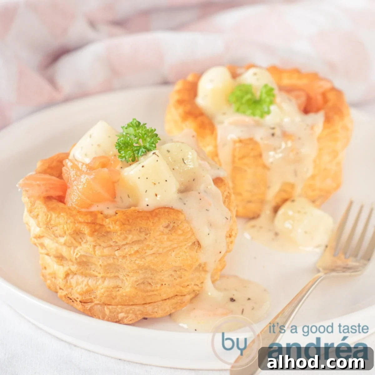 Flaky Pastry Asparagus Ragout 6 A square photo with a white plate with two trays filled with smoked salmon and asparagus ragout that drips over the tray. A golden fork is there.
