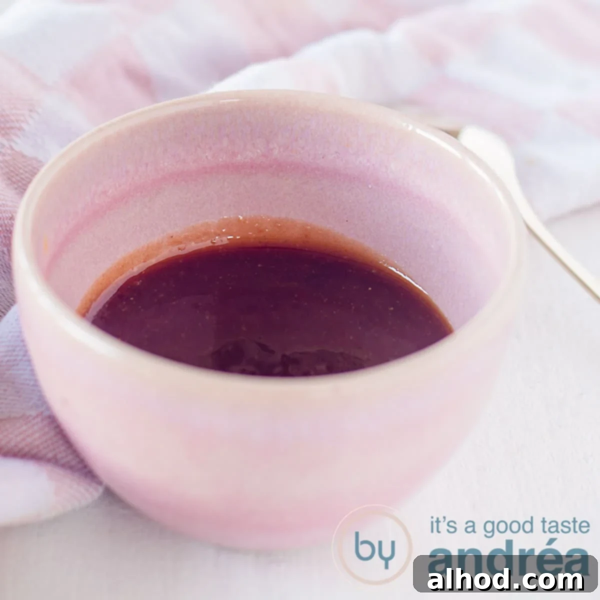 Whip Up Your Own Tonkatsu Sauce 4 A square photo of a pink bowl filled with homemade tonkatsu sauce. A golden spoon is next to it. In the background a pink and white tea towel.