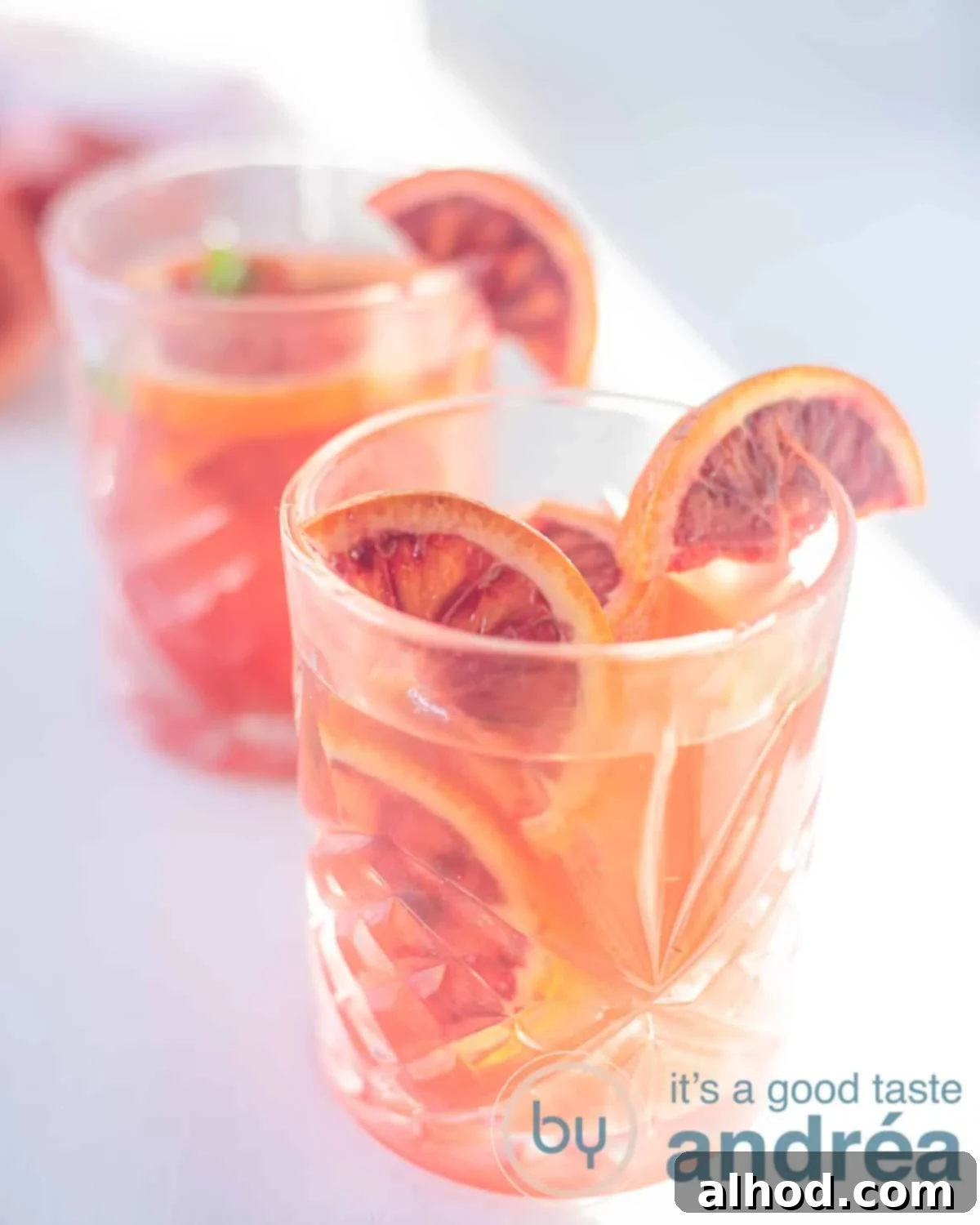 Zesty Blood Orange Iced Tea 5 An elevation photo with two glasses filled with iced blood orange tea slanted one behind the other on a white background