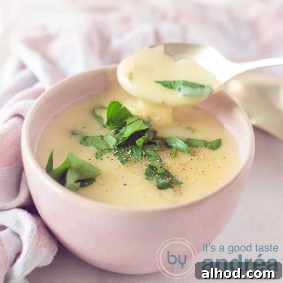 Parmesan Garlic Perfection 6 A square photo of a pink container filled with parmesan cheese sauce with garlic and parsley. A spoon with sauce in the foreground. In the background a pink and white tea towel.