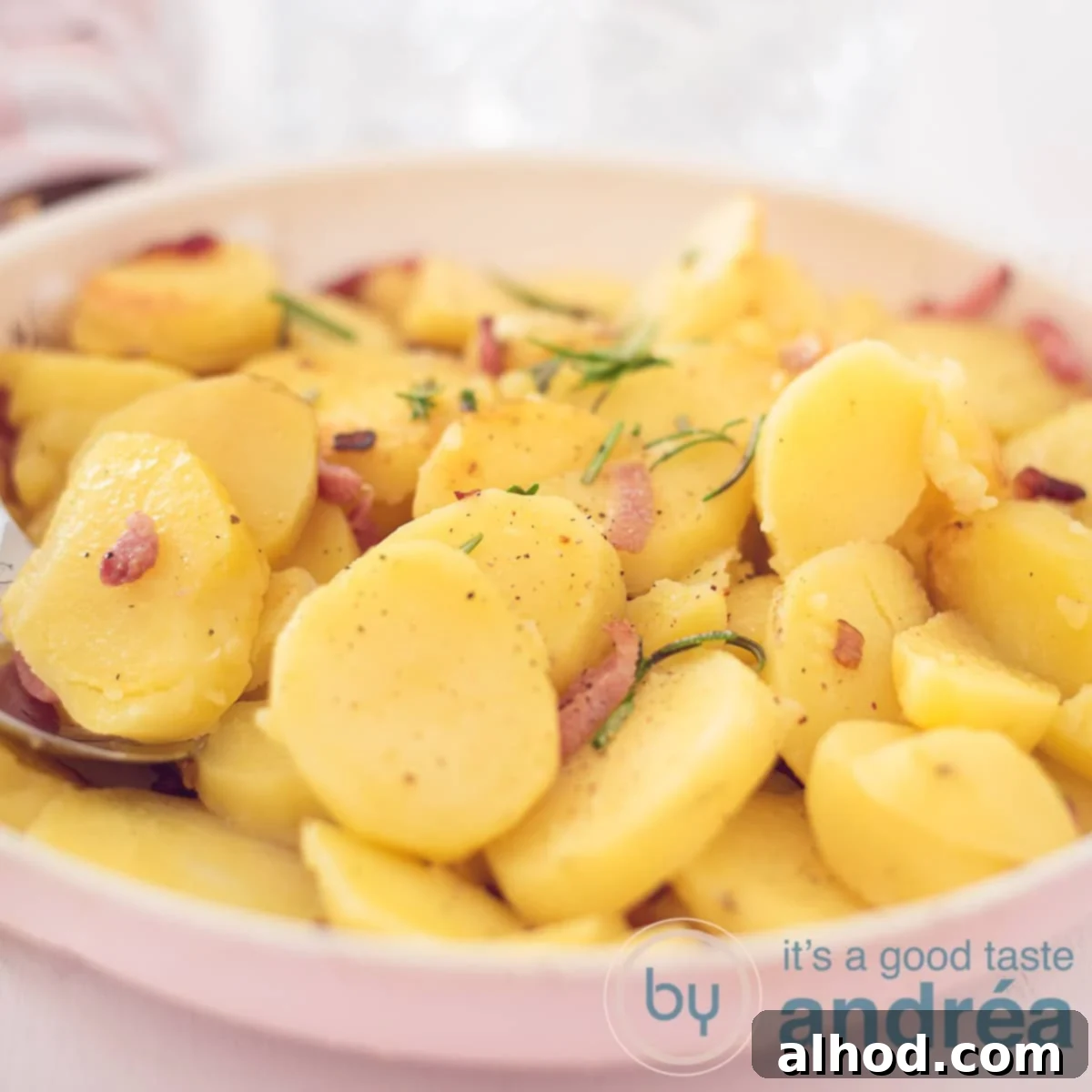 Classic German Fried Potatoes 6 A square photograph of a frying pan with fried potatoes, rosemary, onions and bacon bits. a white background.