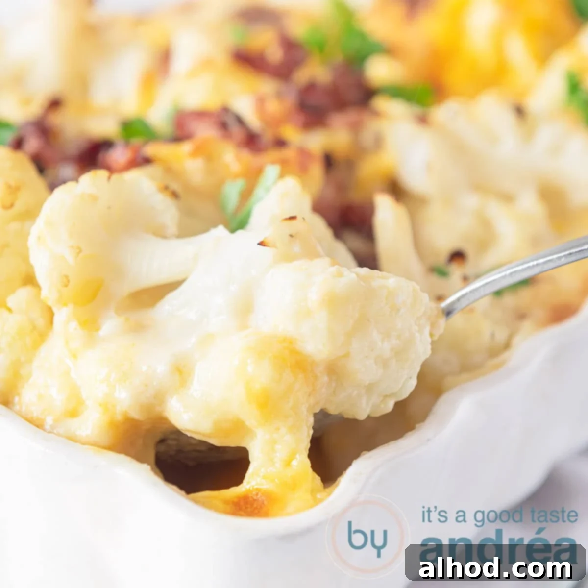 Savory Cheesy Sausage and Cauliflower Bake 6 Close-up of a square baking dish filled with Cheesy Sausage and Cauliflower Casserole, with a portion scooped out, highlighting the layers of mashed potatoes, sausage, and cheesy gratin.