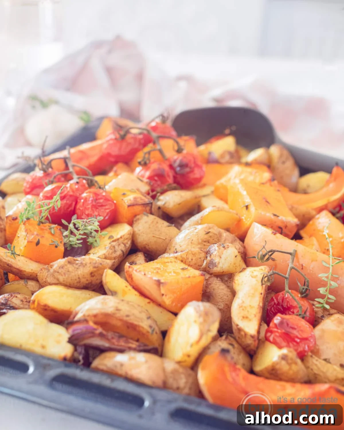 Golden Roasted Pumpkin and Potatoes 4 An overhead photo showing part of a baking sheet with roasted potato, pumpkin, tomatoes, thyme and red onion.