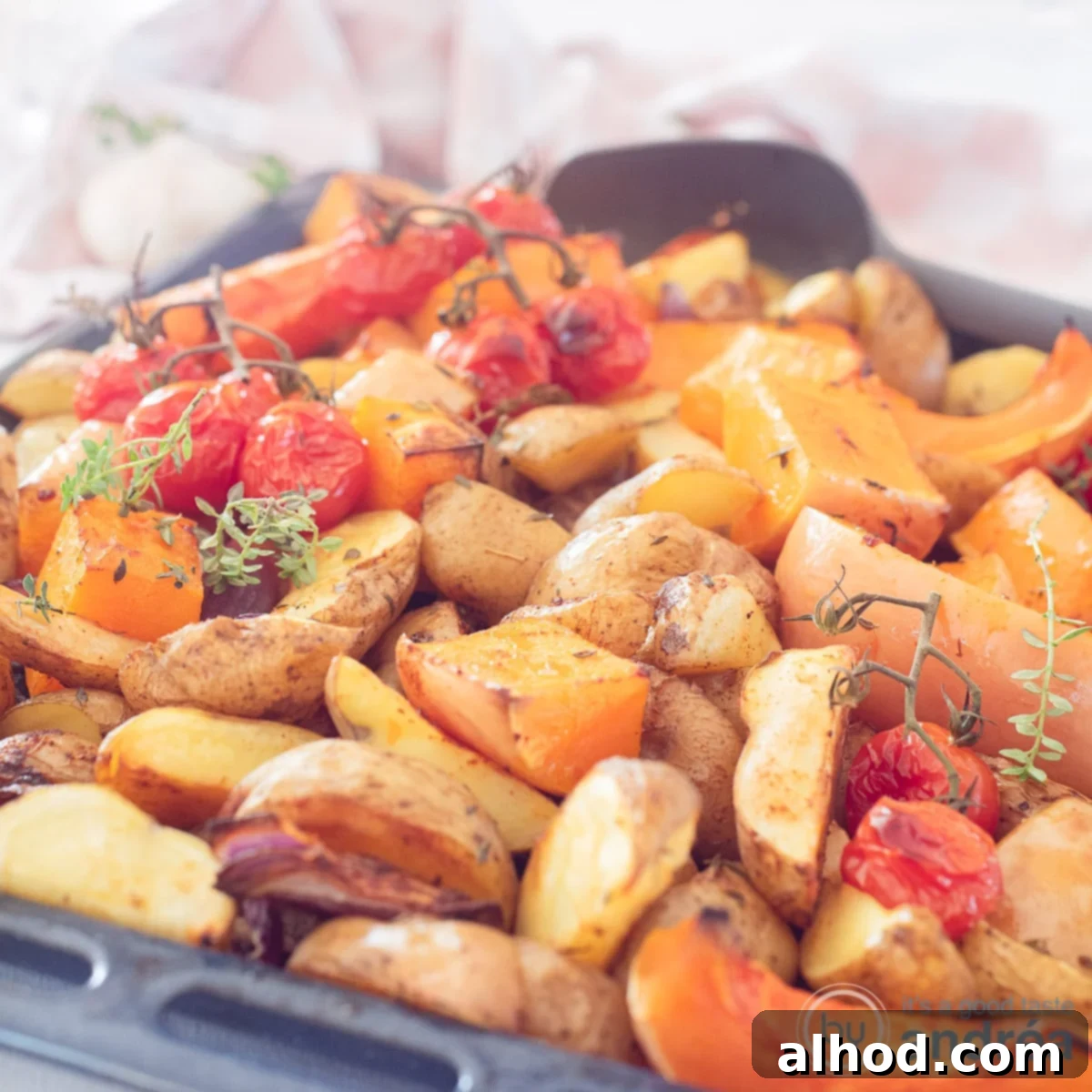 Golden Roasted Pumpkin and Potatoes 5 A square photo with a baking tray with pumpkin, cherry tomatoes, potatoes and onion. Thyme flavors everything.