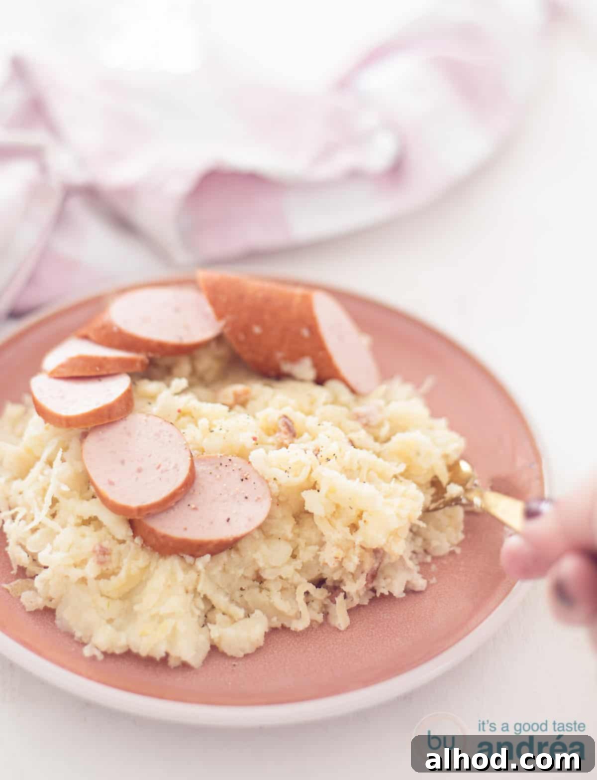 Hearty Dutch Sauerkraut Potato Mash 3 Een hoogtefoto met een bord gevuld met zuurkool stamppot, spekjes en plakjes rookworst. Een vork schept een hap.